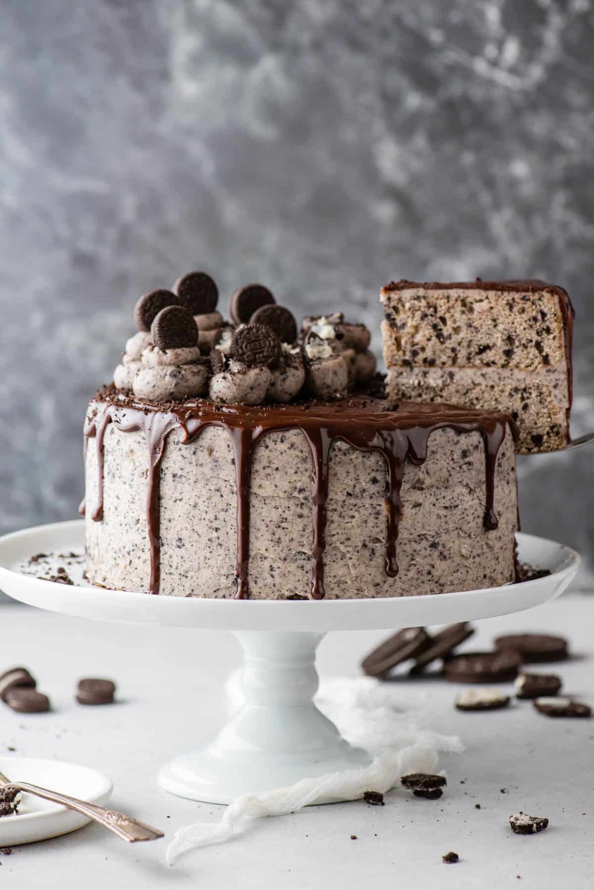 Whole Oreo cake on cake stand with slice being removed