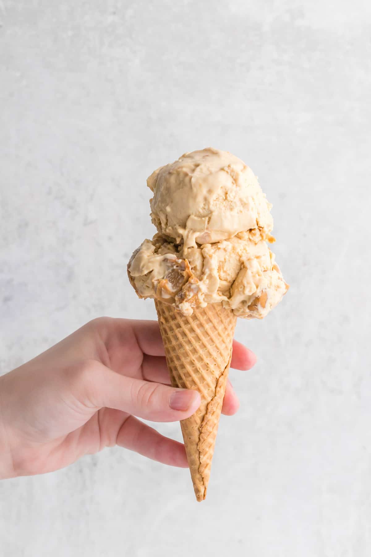 Hand holding a cone of peanut butter ice cream