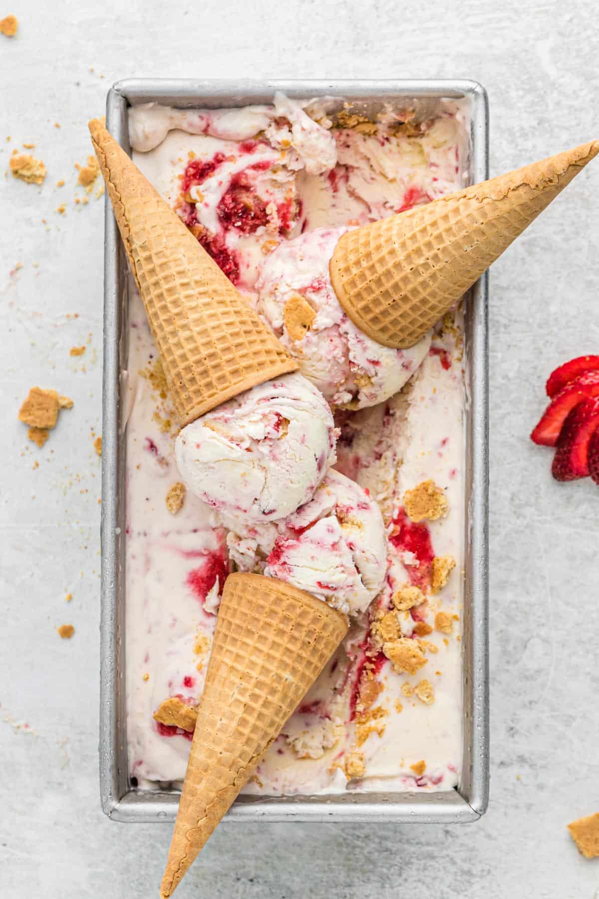 cheesecake ice cream in metal loaf pan with 3 ice cream cones