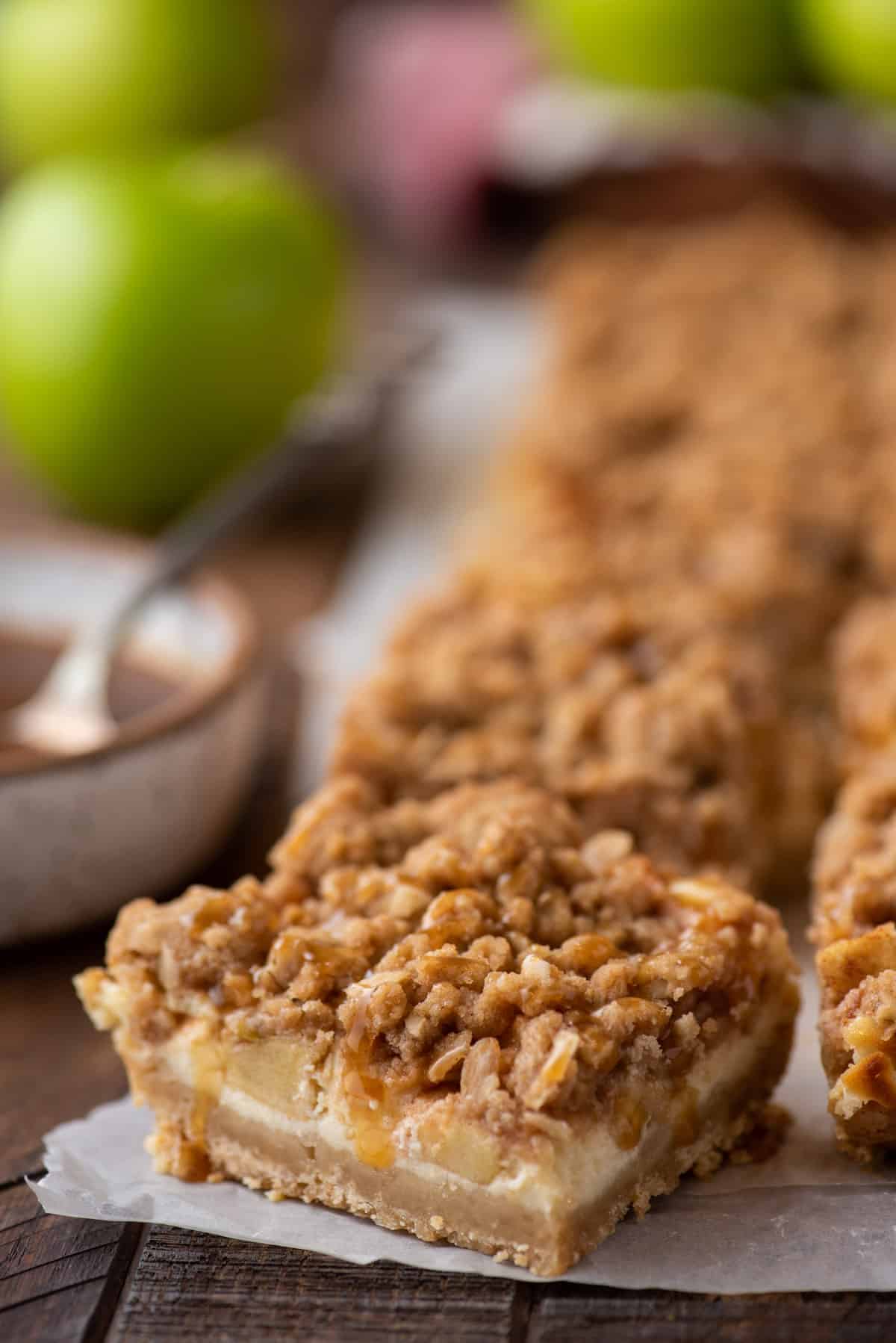 Caramel apple cheesecake bars on parchment paper