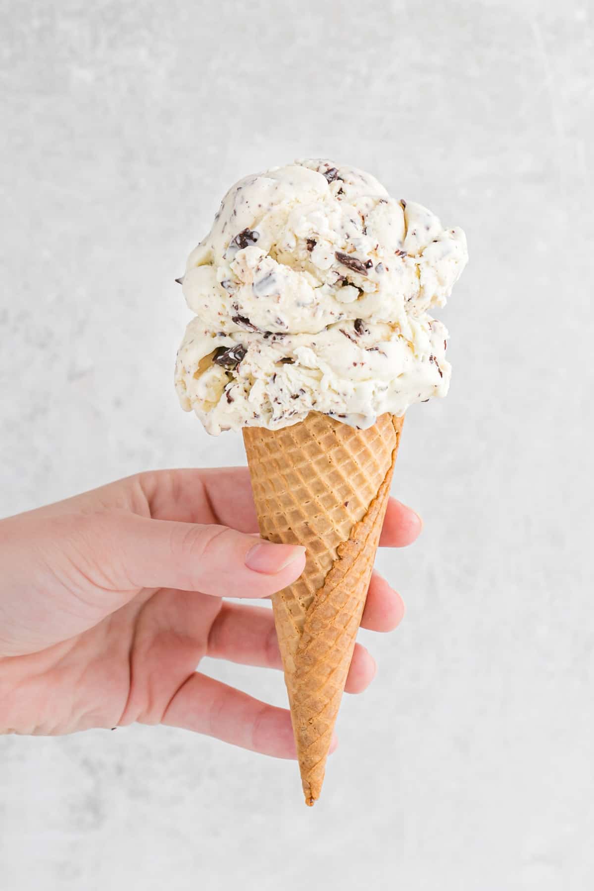 hand holding ice cream cone with 2 scoops of chocolate chip ice cream