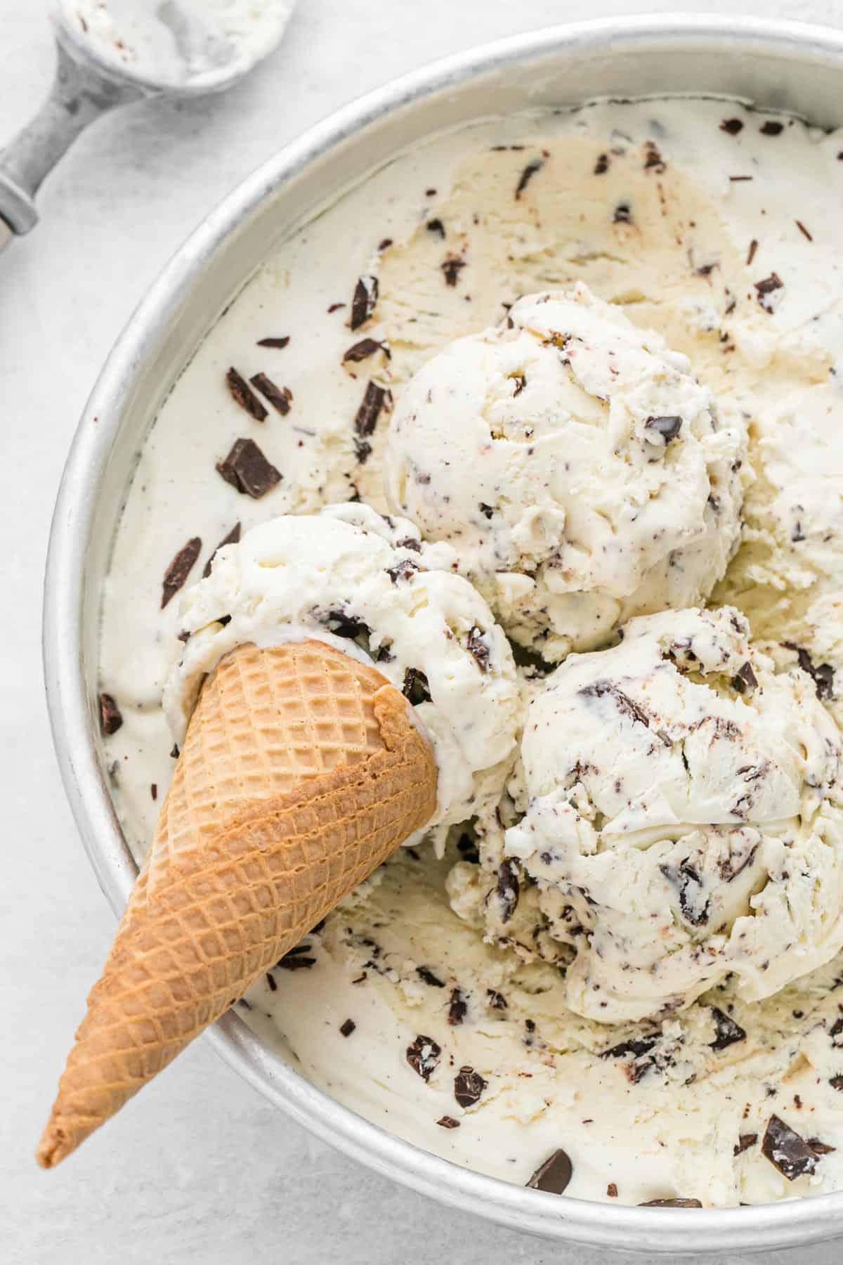 no churn chocolate chip ice cream in round cake pan with 3 scoops and 1 ice cream cone