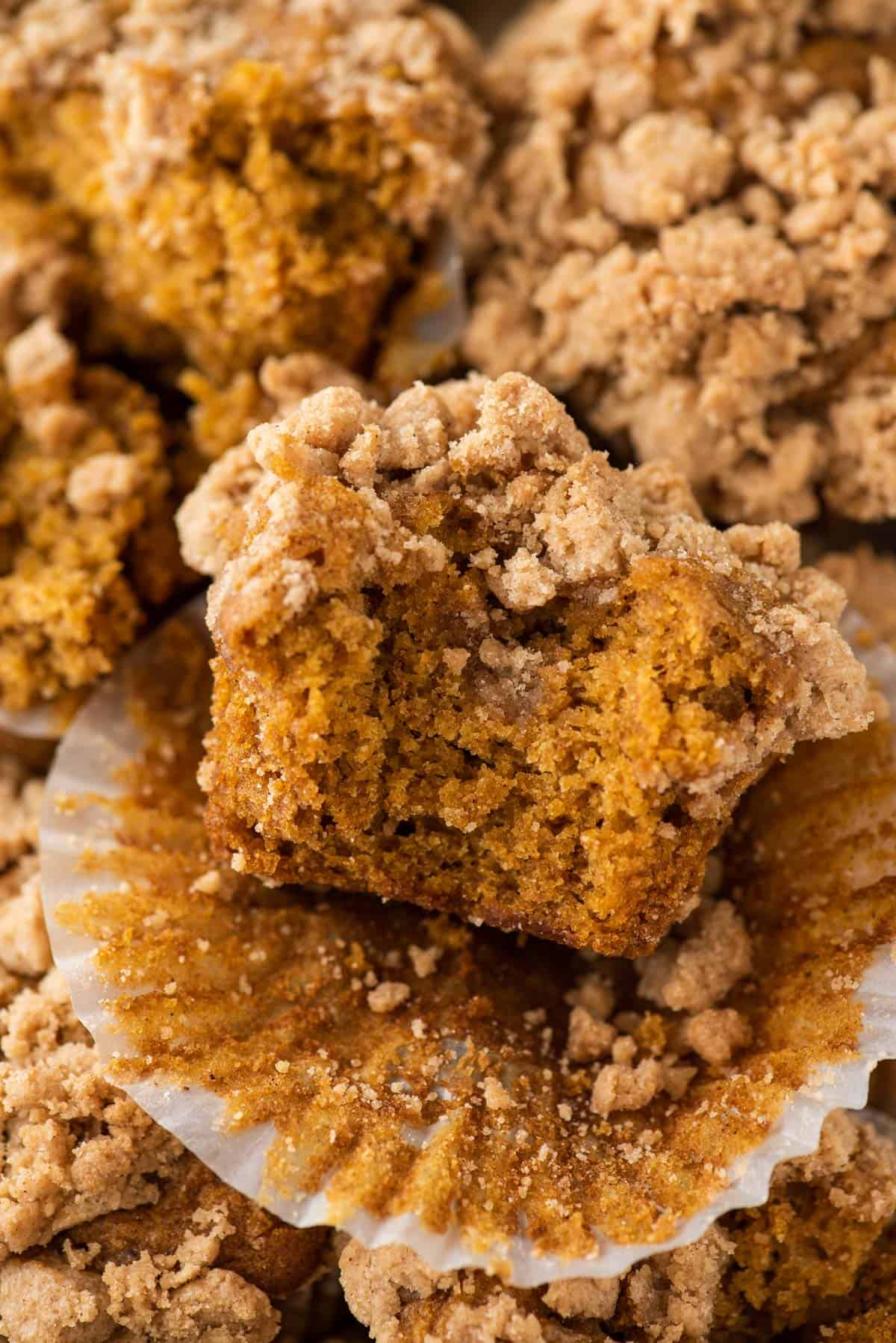 a single pumpkin muffin with streusel topping with bite taken out of it