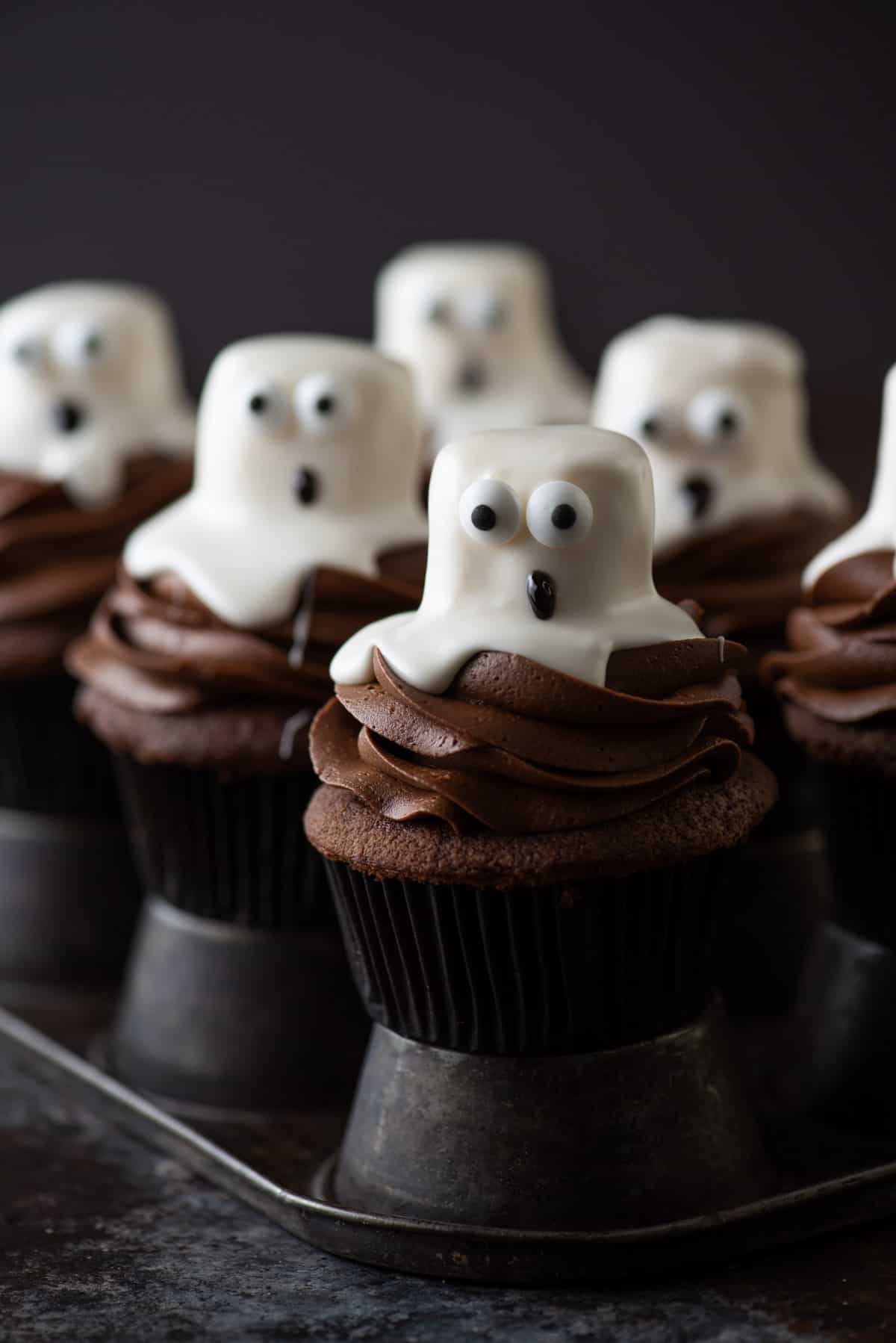 ghost cupcakes sitting on metal muffin pan