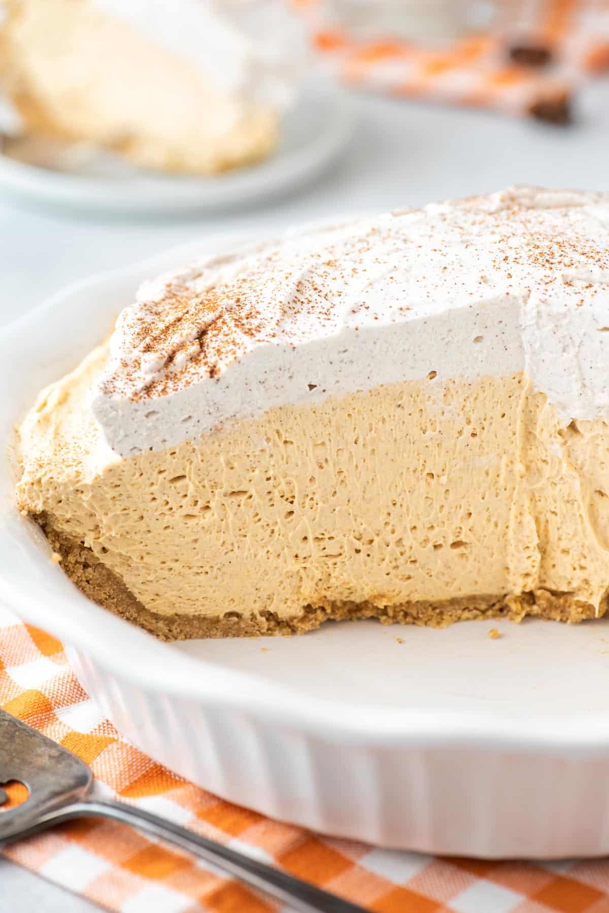 A light and creamy piece of no bake pumpkin pie sits on a white dessert plate.