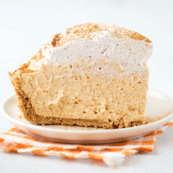 A light and creamy piece of no bake pumpkin pie sits on a dessert plate on top of an orange checkered napkin.
