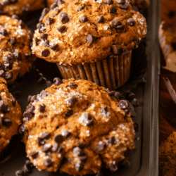 A tray of freshly baked Pumpkin Chocolate Chip Muffins topped with sugar crystals and chocolate chips, labeled “Fall Muffin: Pumpkin Chocolate Chip Muffins” at the bottom.