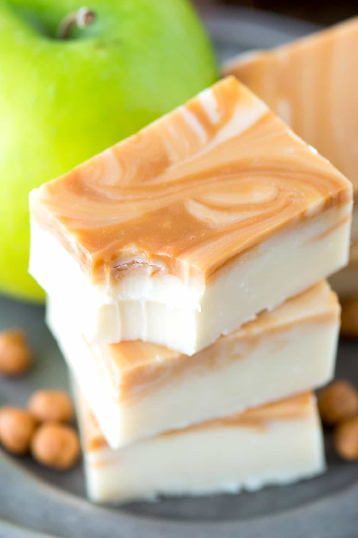 caramel apple fudge slices in a stack with bite removed from top fudge piece