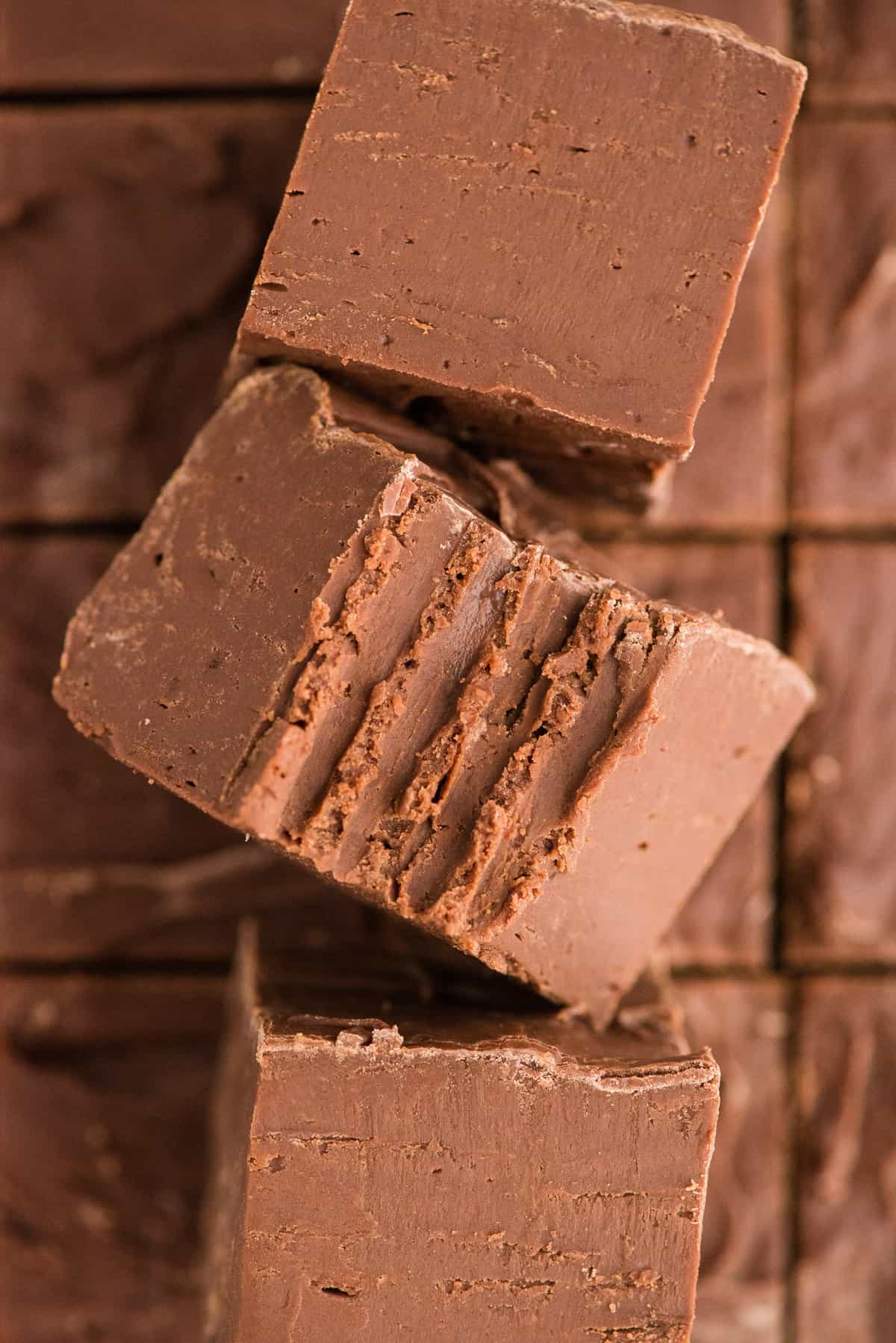 3 pieces of chocolate fudge cut into squares with the center piece has a bite removed