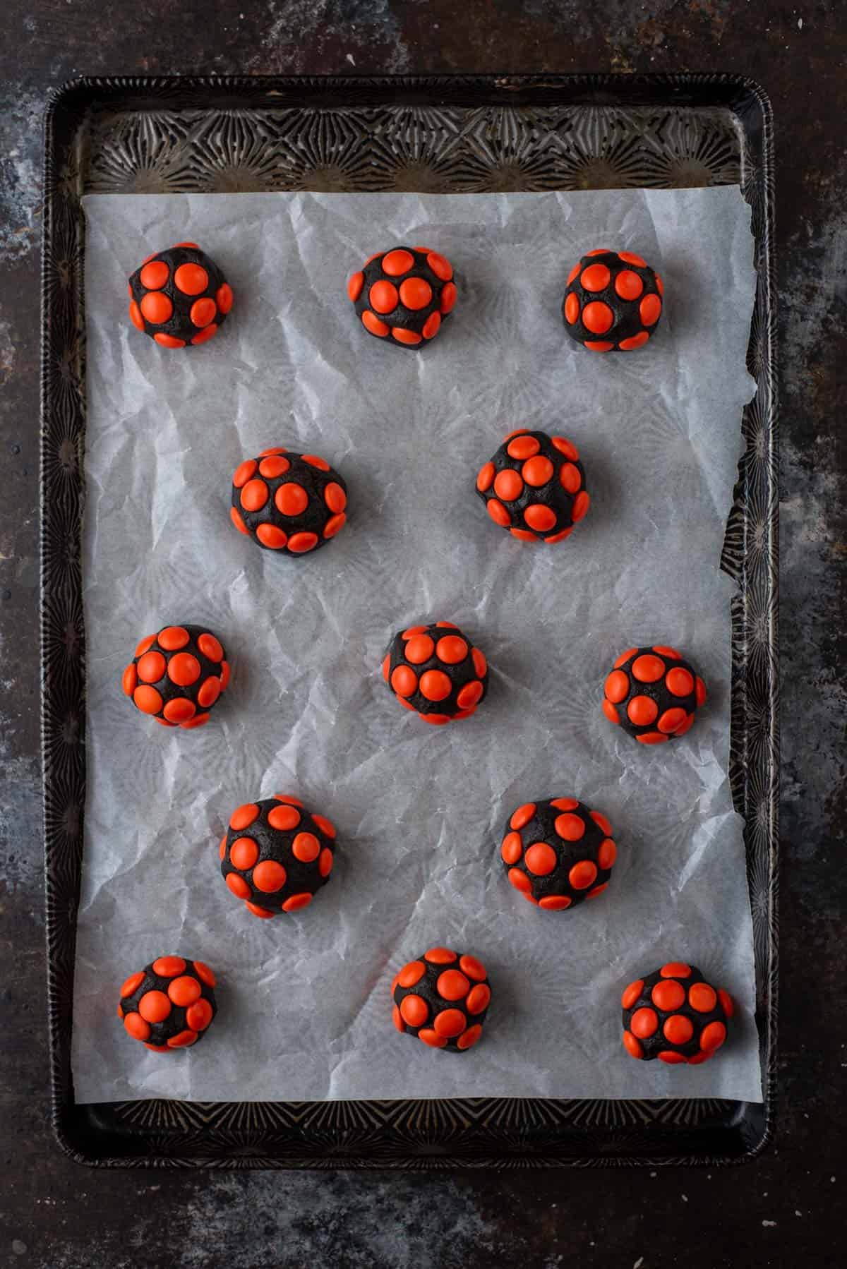 Balls of chocolate cookie dough covered in orange M&Ms