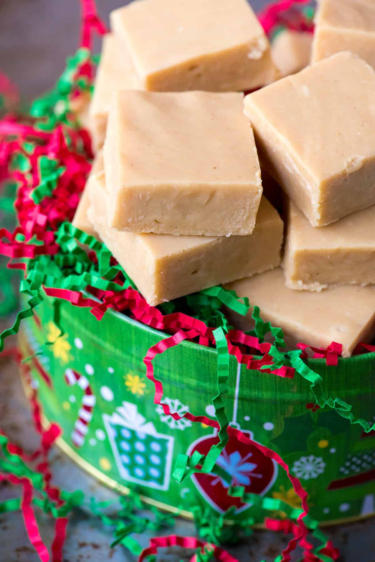 slices of peanut butter fudge in a christmas tin with red and green crinkle paper