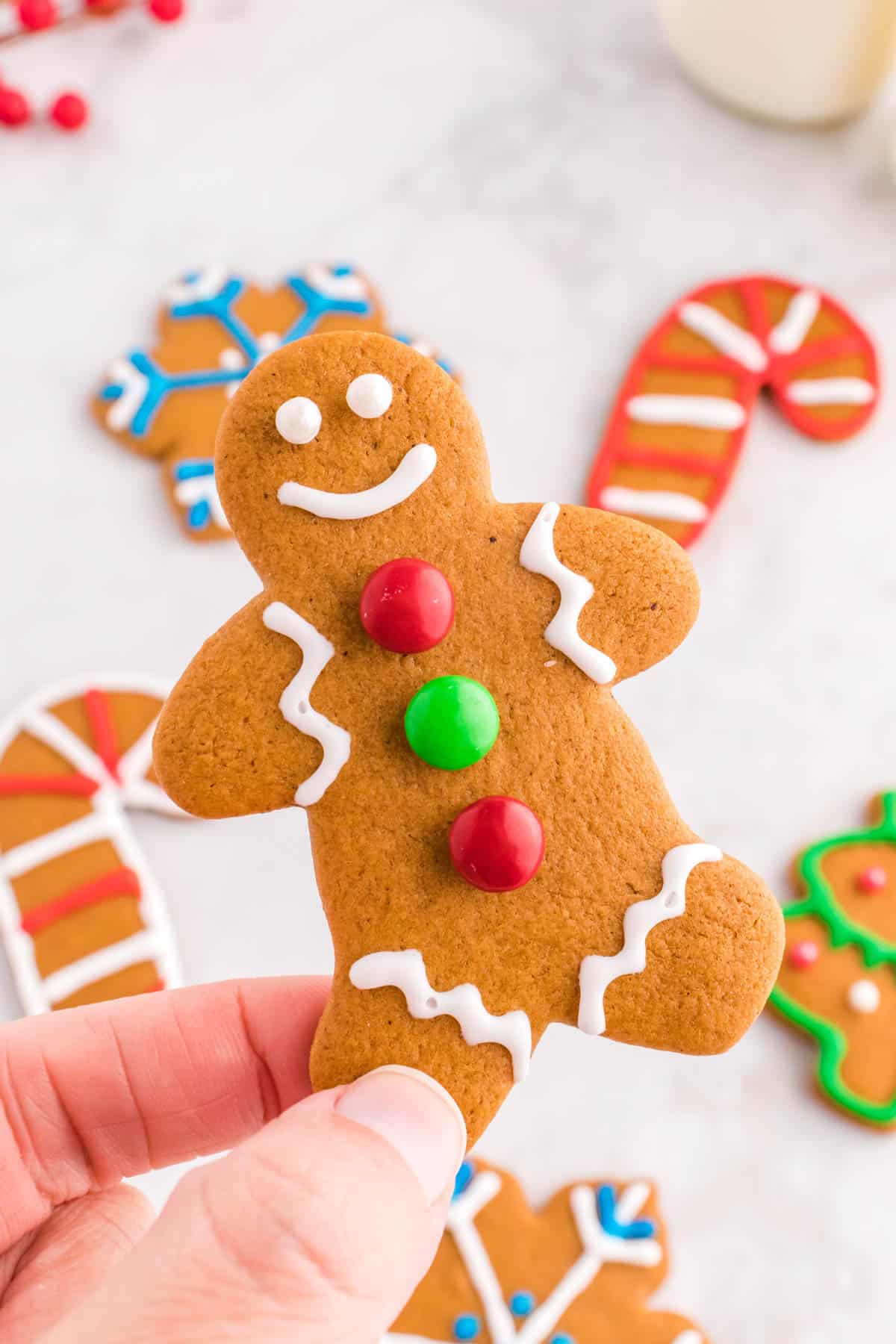 hand holding gingerbread cookie man with M&M buttons