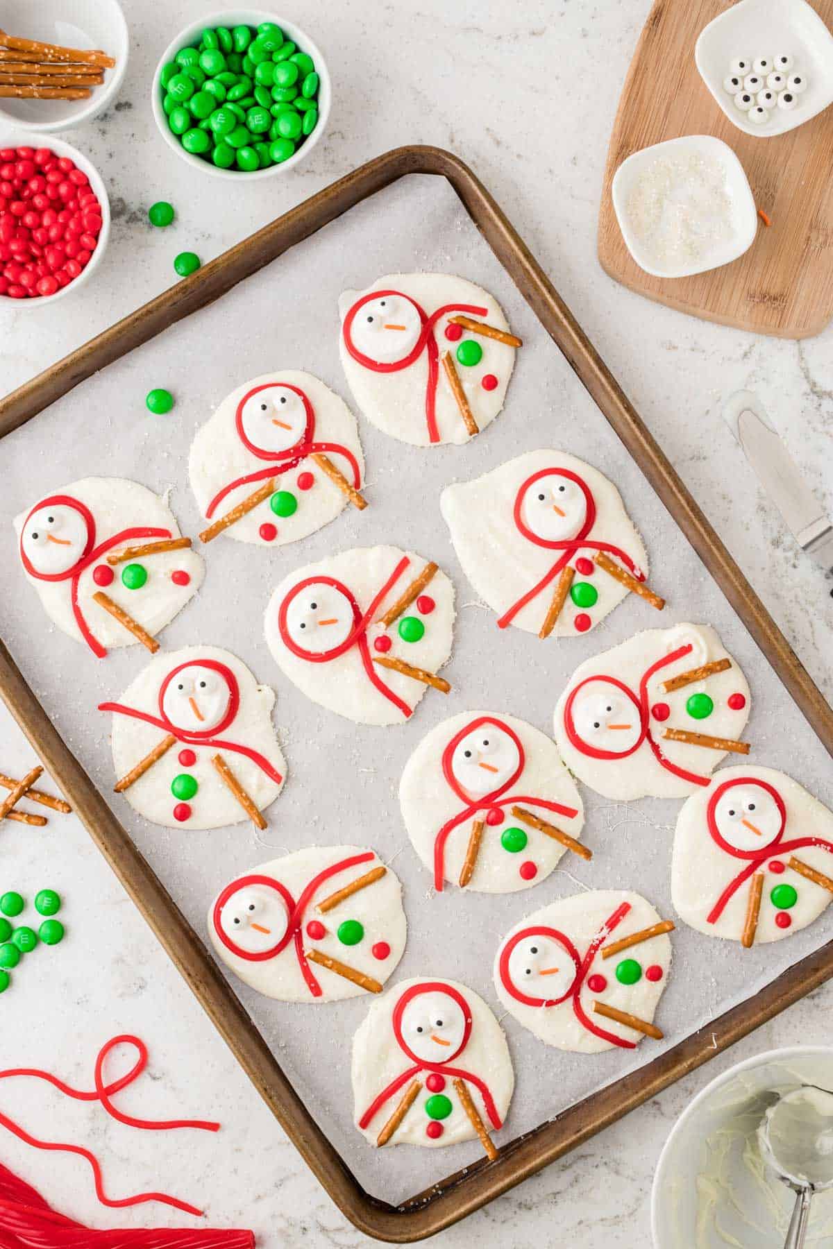 dollops of melted white chocolate arranged in grid on parchment paper to look like snowmen