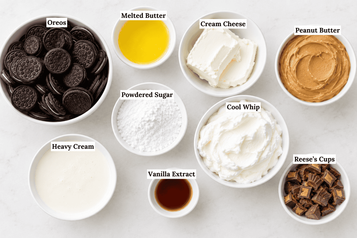 Nine bowls on a white surface, each labeled: Oreos, melted butter, cream cheese, peanut butter, powdered sugar—everything you need for the ultimate no bake peanut butter pie with cool whip and chopped Reeses cups.