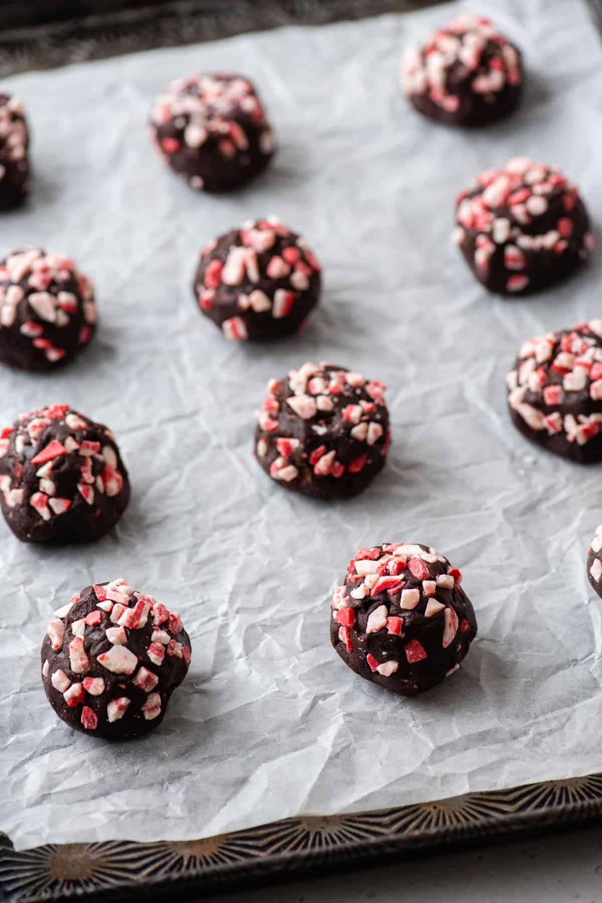 Balls of chocolate peppermint cookie dough on a baking sheet