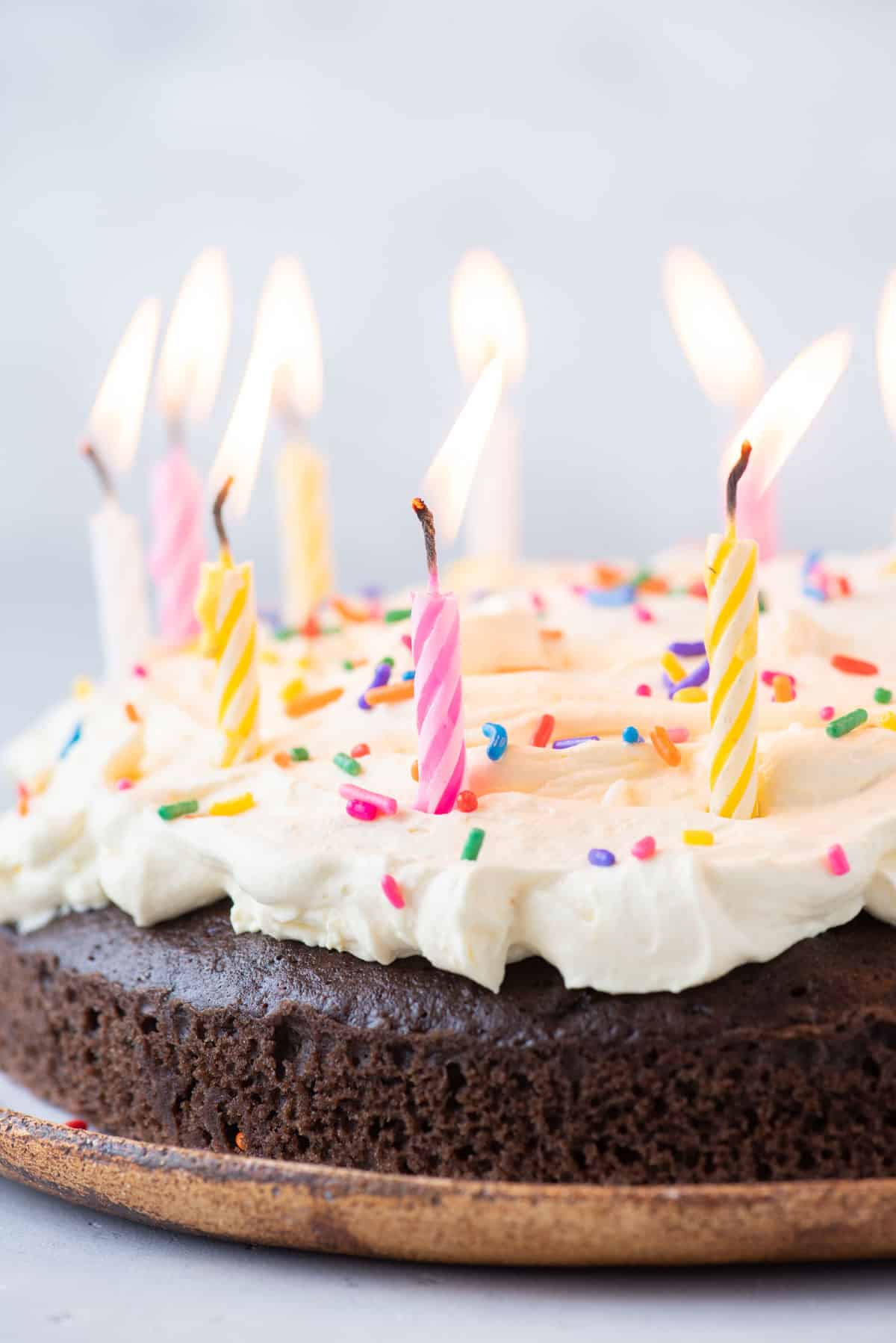 chocolate cake topped with cool whip frosting with sprinkles and lit birthday candles on top