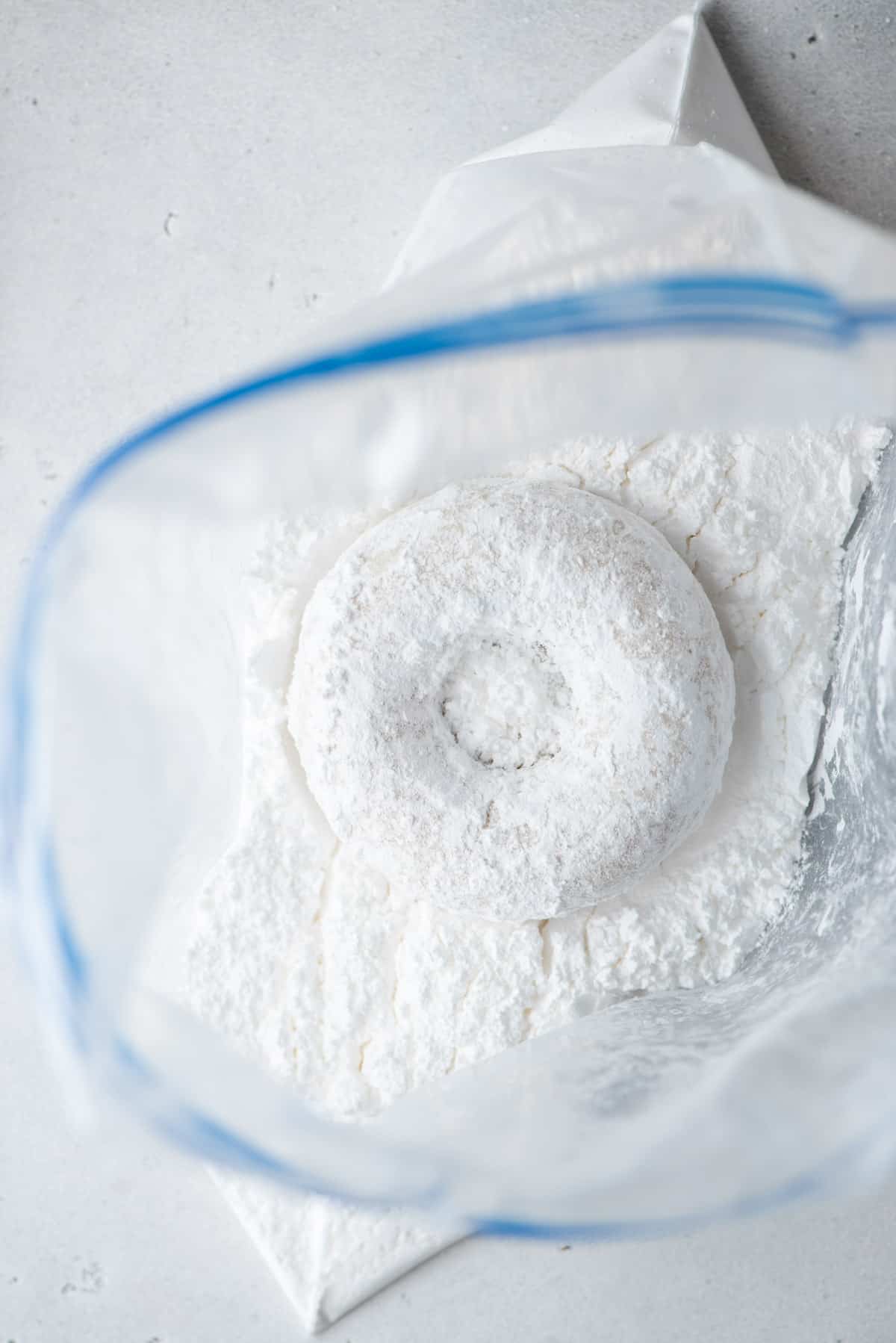 Donut in a plastic bag full of powdered sugar