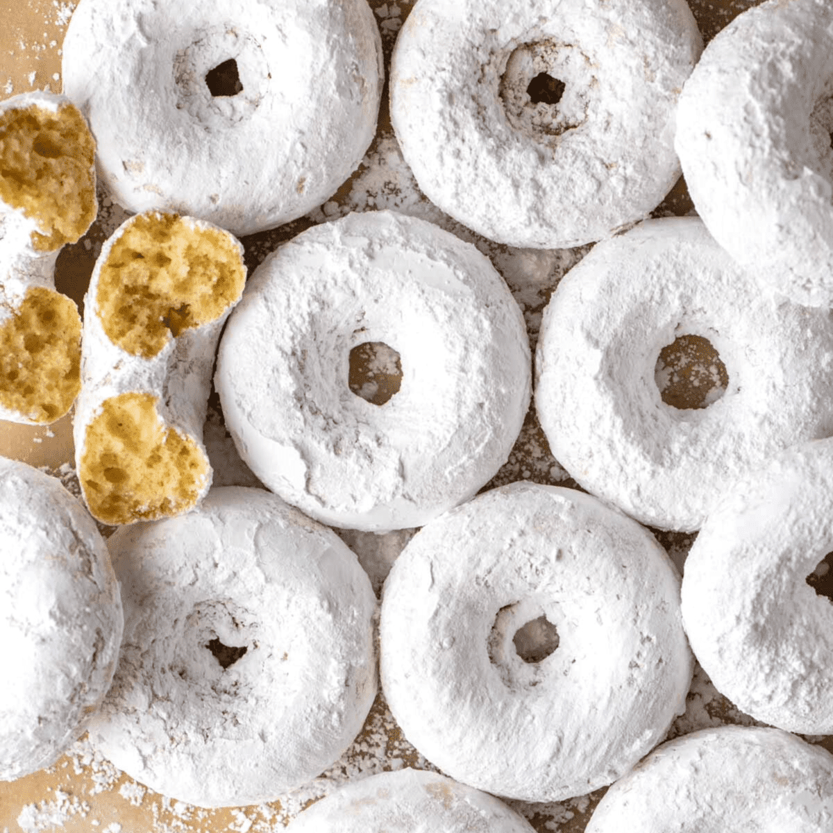 powdered sugar donuts arranged on brown paper