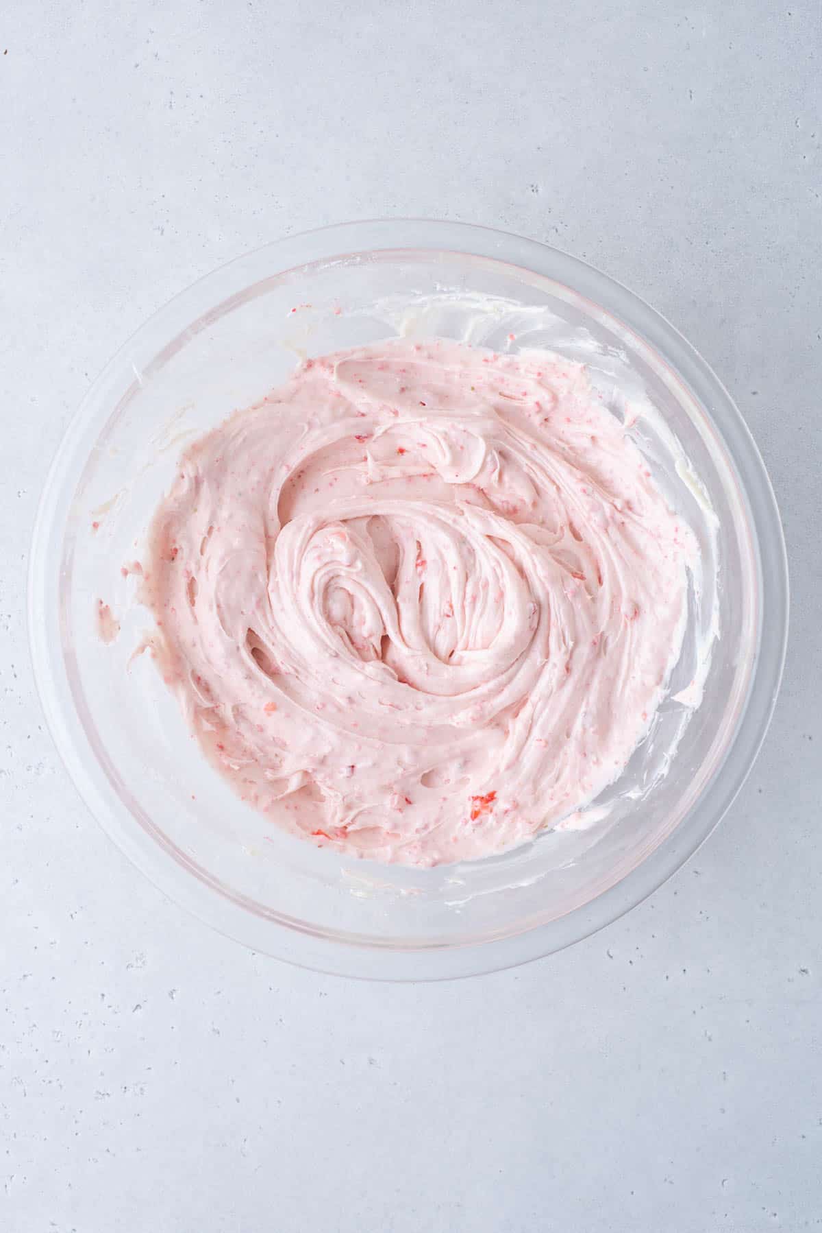 Strawberry Frosting in a clear glass bowl on a white surface