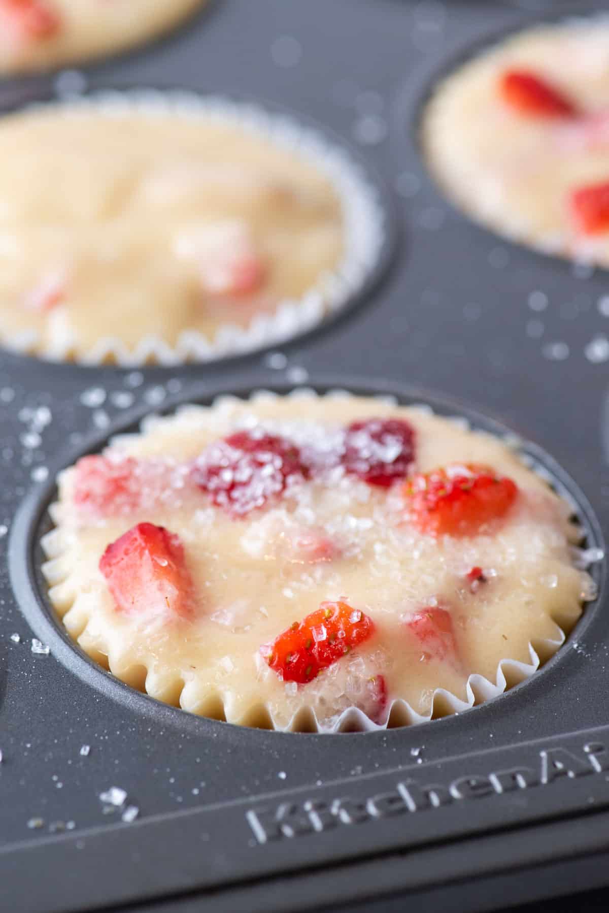 strawberry muffin batter in a paper muffin cup in a muffin pan