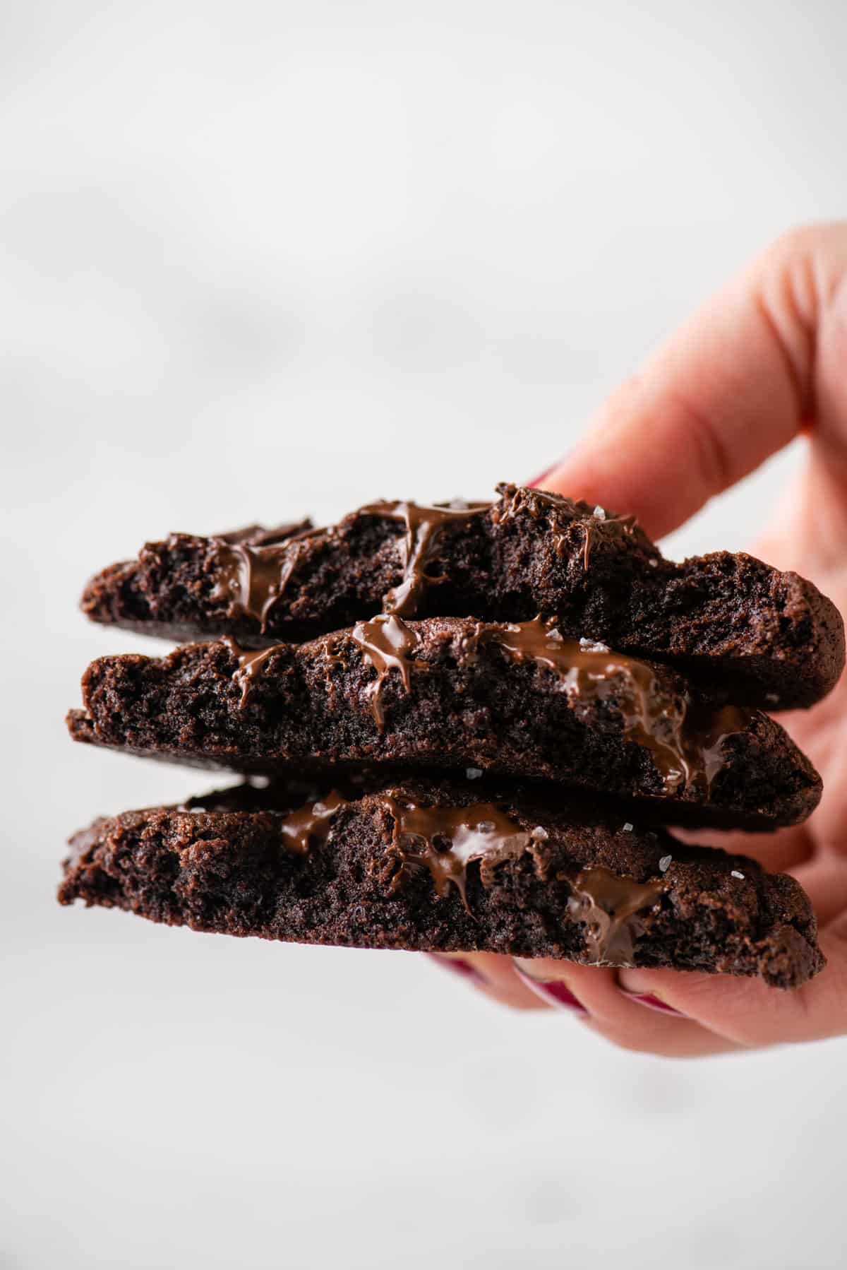 A hand holding three halves of chocolate cookies