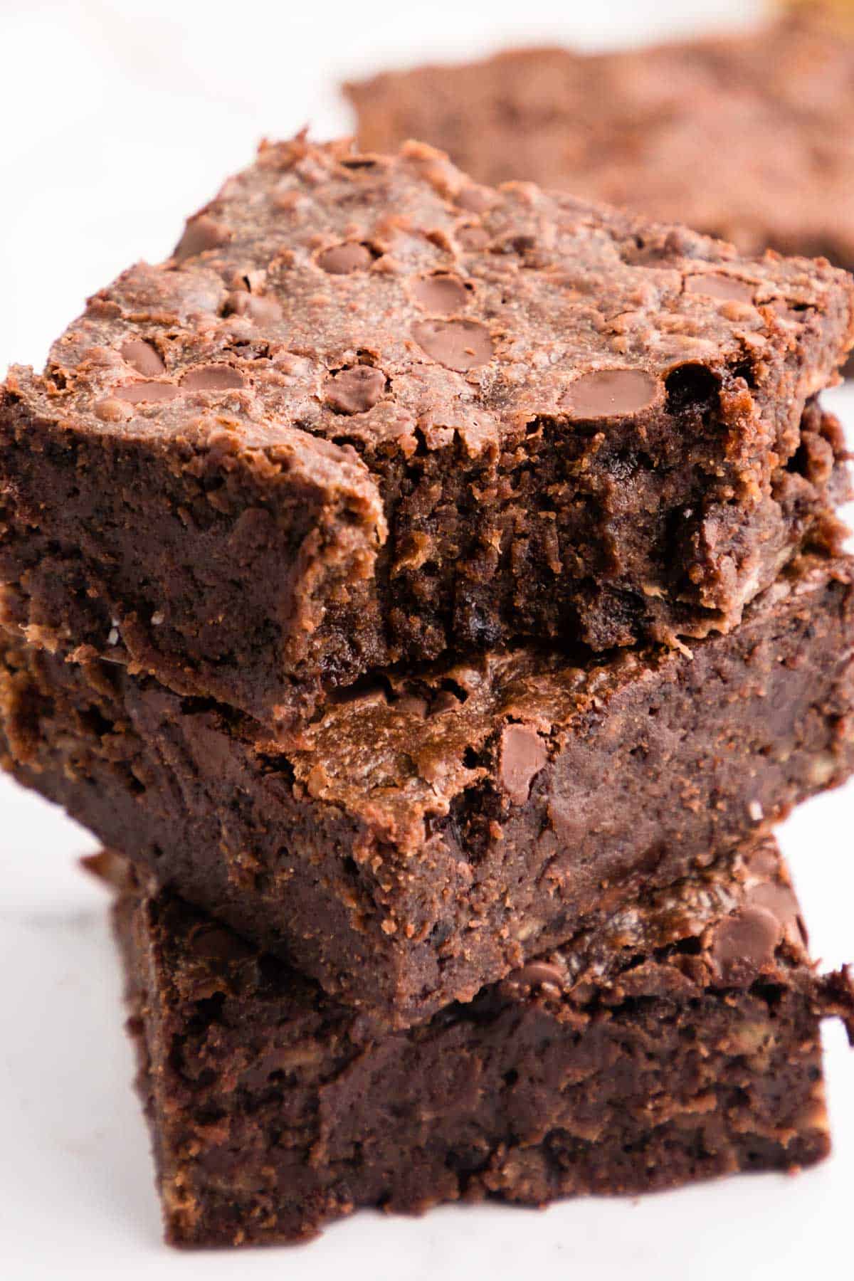 A stack of three banana brownies, with a bite out of the one on top
