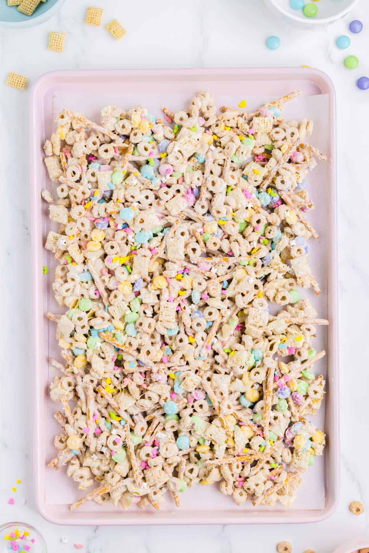 easter bunny bait snack mix spread out on a pink baking sheet