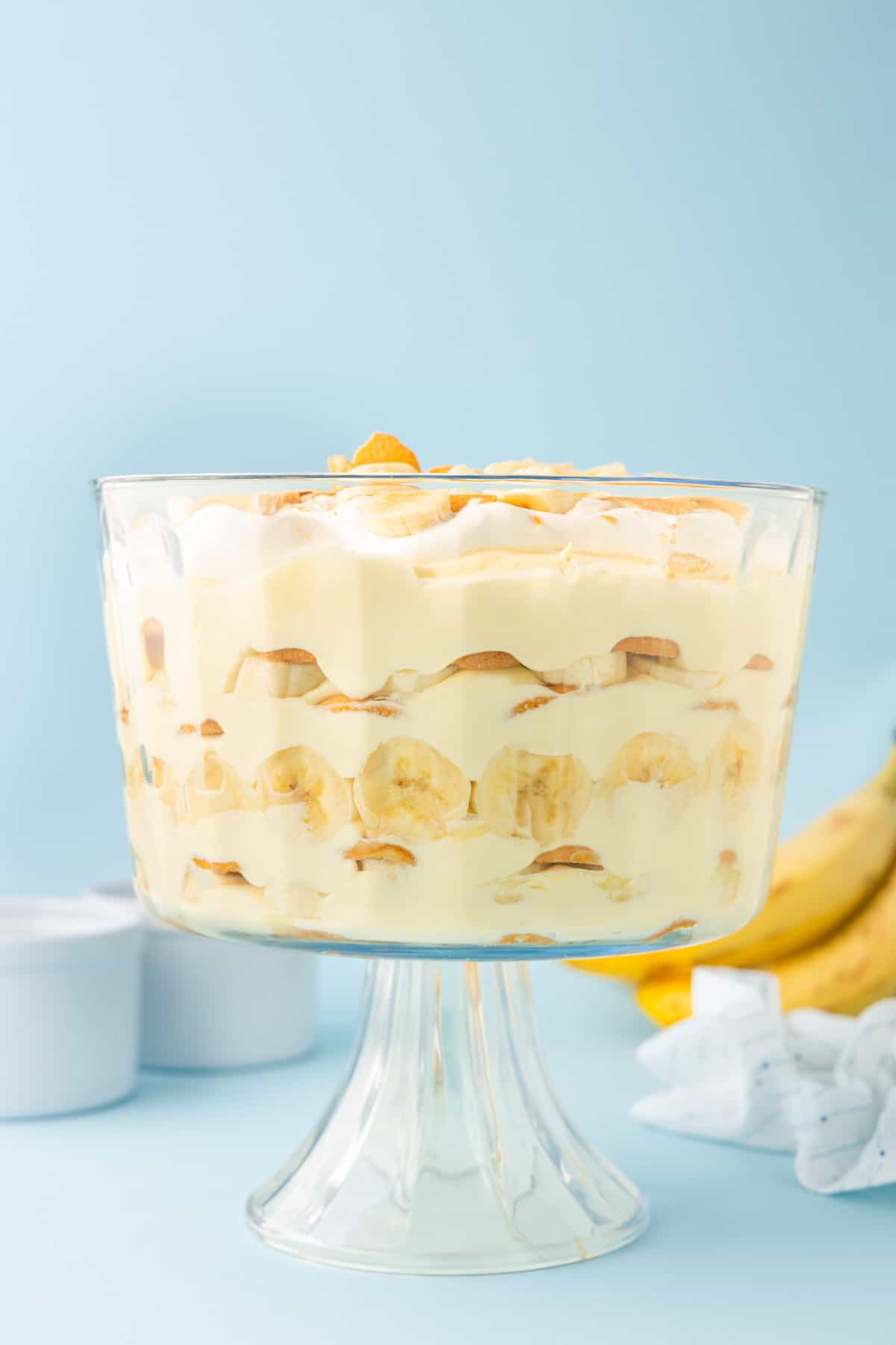 trifle dish with banana pudding layered inside of it against a blue background