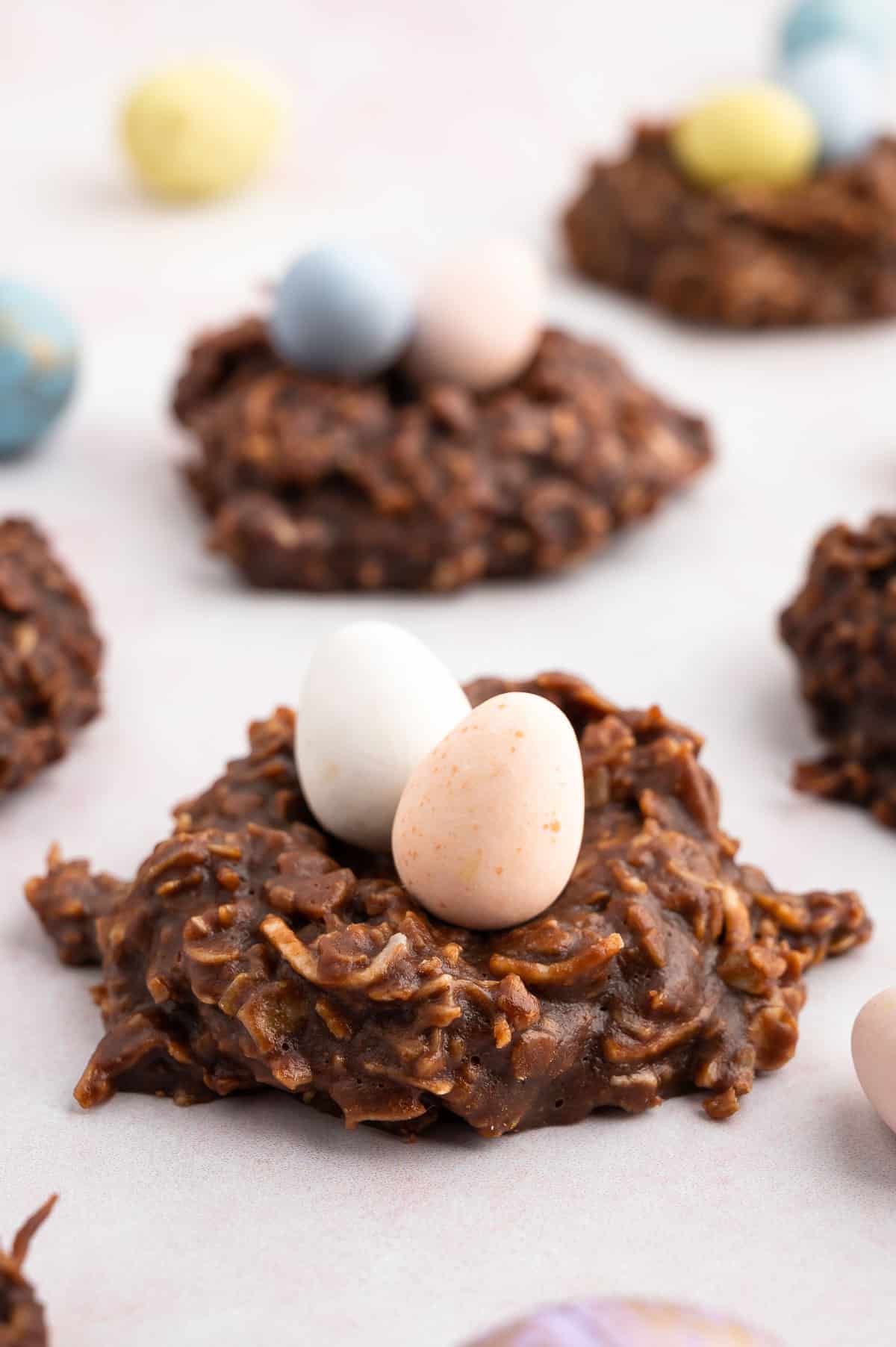 no bake birds nest cookies (no bake oatmeal cookies topped with candy easter eggs) on parchment paper