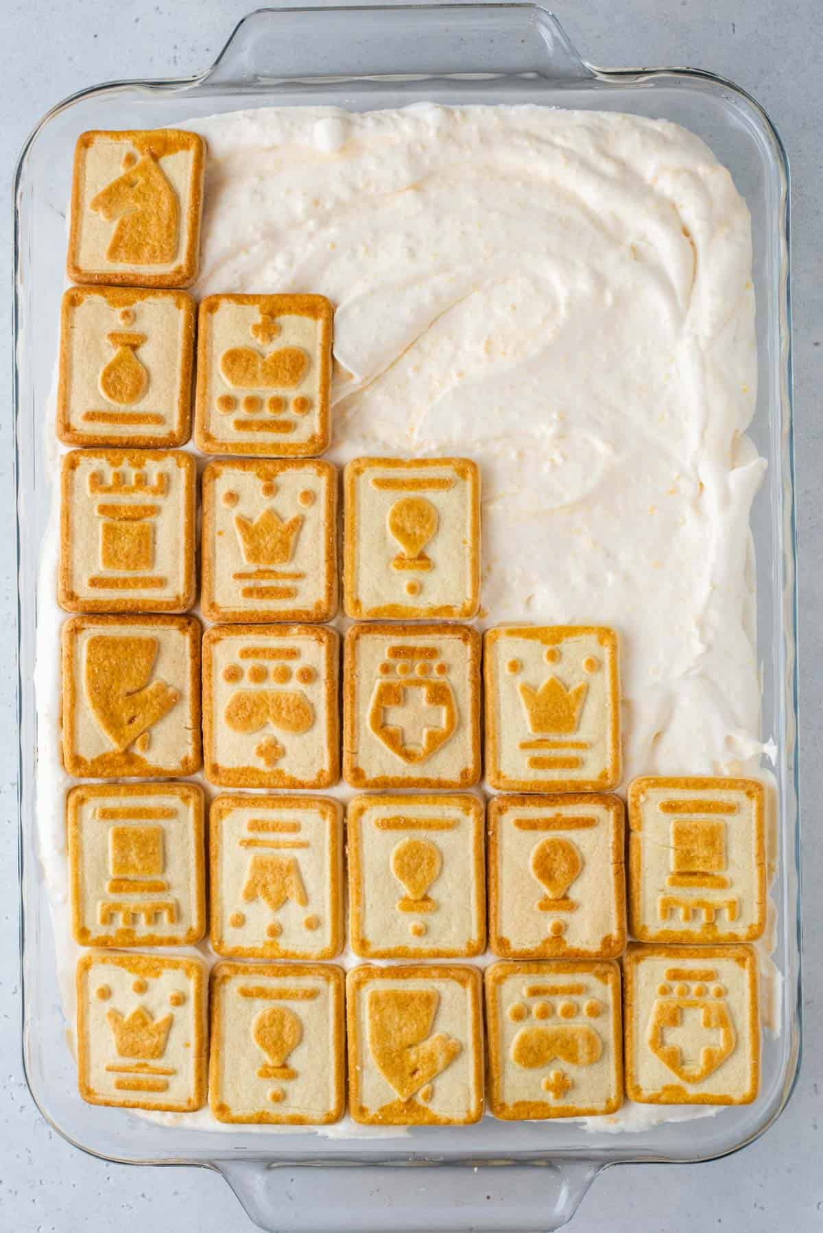 banana pudding in a clear dish with chessman cookies on top of half of the dish