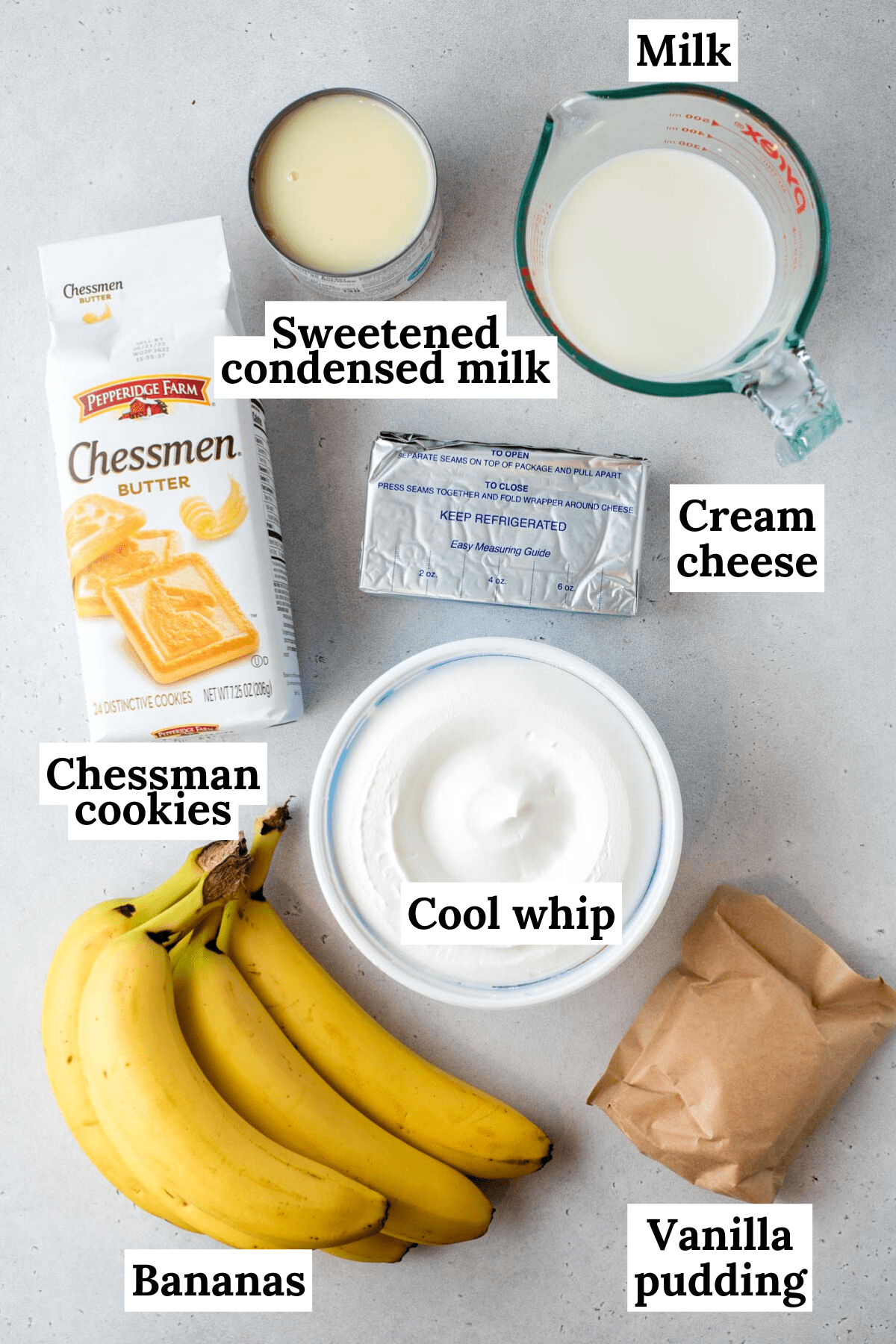 ingredients for banana pudding arranged on a white counter including chessman cookies, cool whip, vanilla pudding mix, bananas, milk, sweetened condensed milk and cream cheese