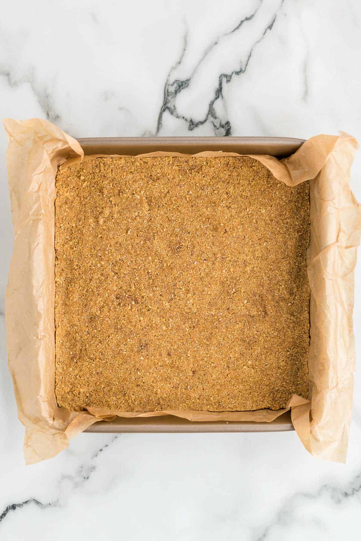 graham cracker crust in a square pan lined with parchment paper