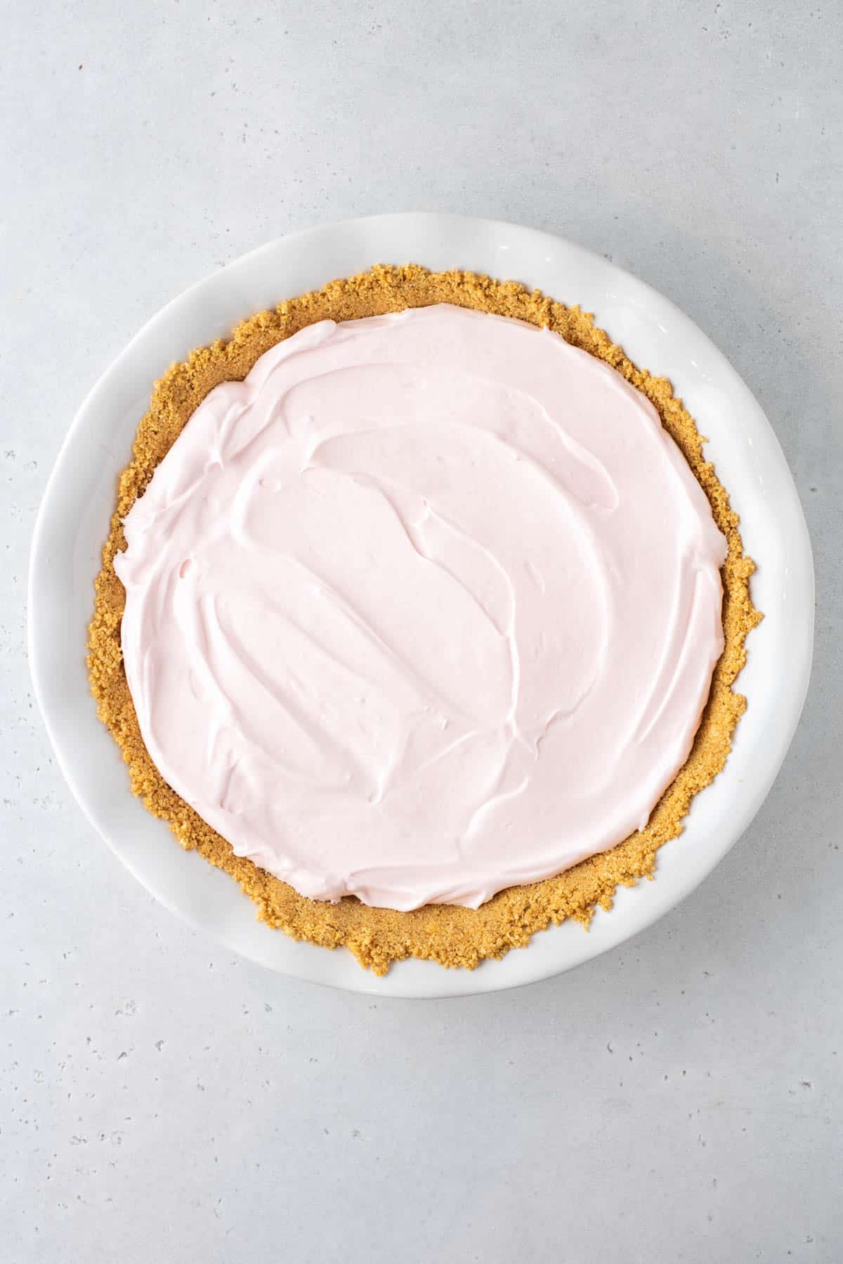 kool aid pie filling with graham cracker crust in a white pie dish