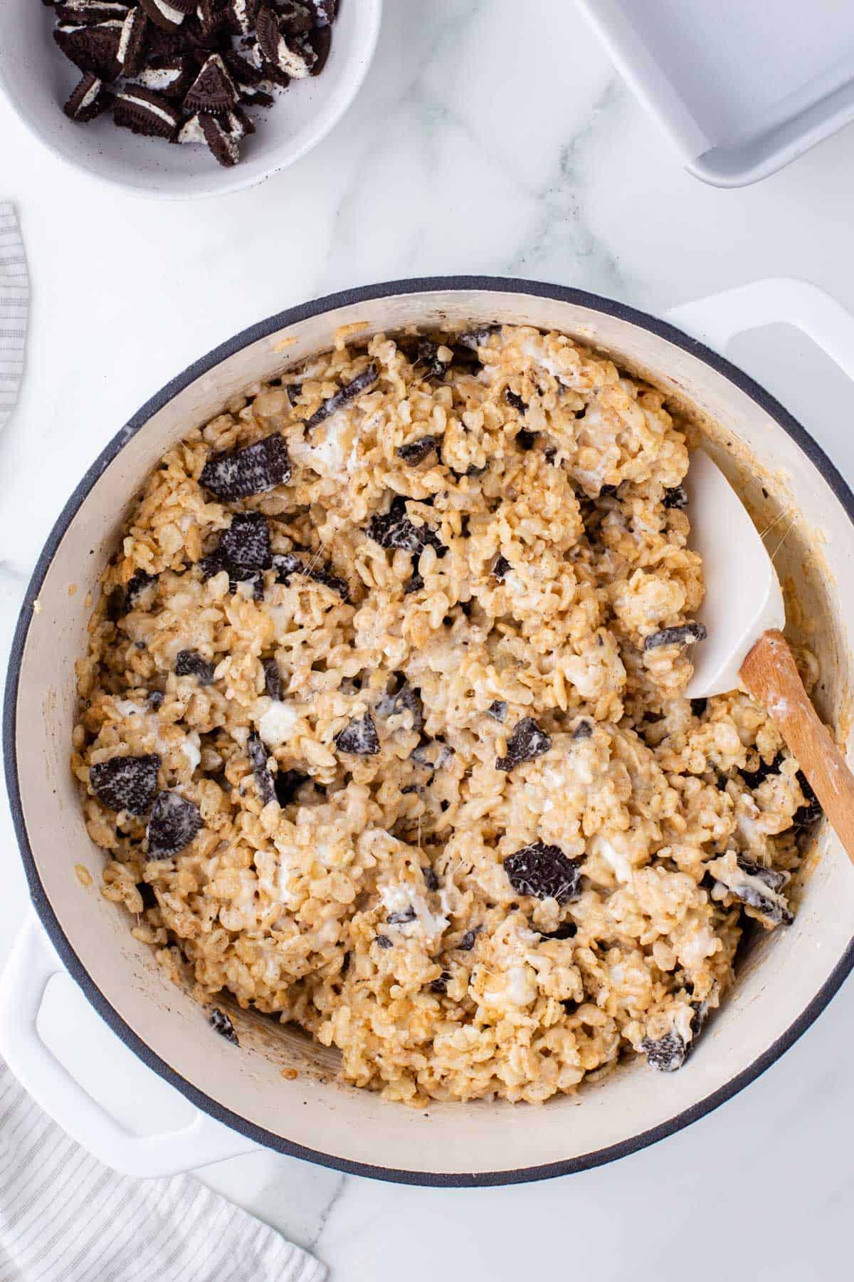 oreo rice krispie treats mixture in a white pot with a wood spatula