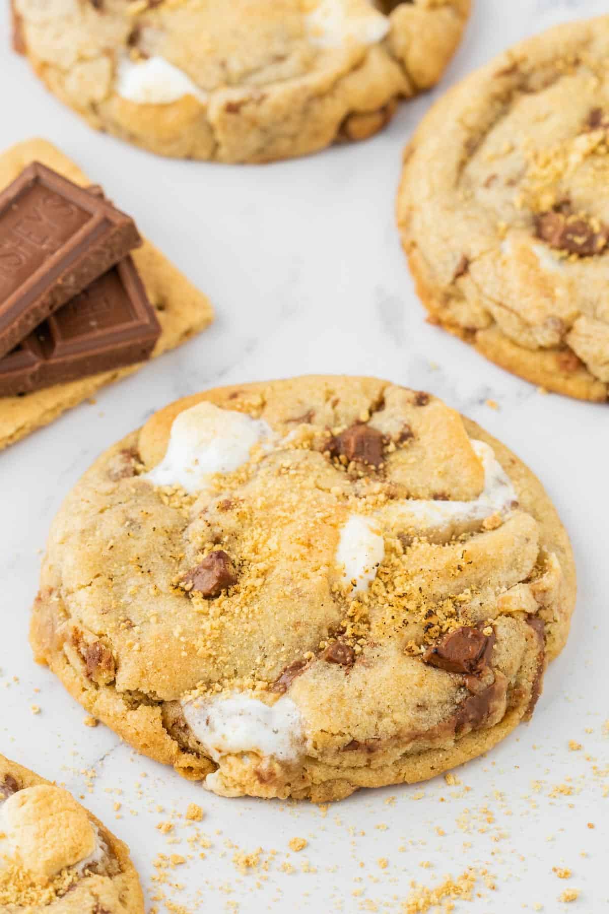 smores cookies arranged by a graham cracker with hershey bar pieces on top of it