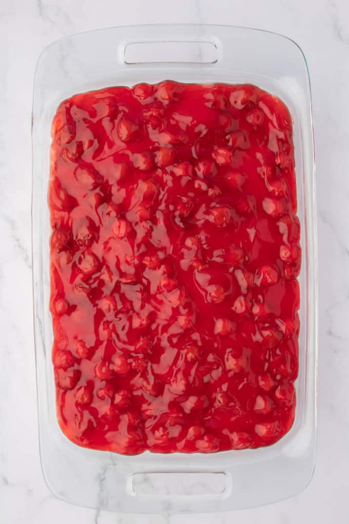 cherry delight topping with cherry pie filling in a clear baking dish