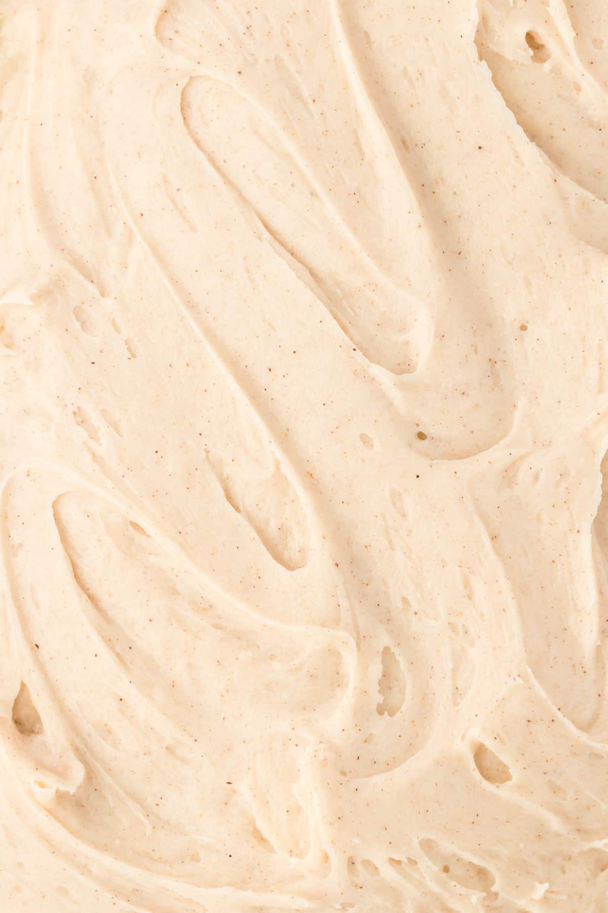 close up of cinnamon cream cheese frosting spread into a flat layer