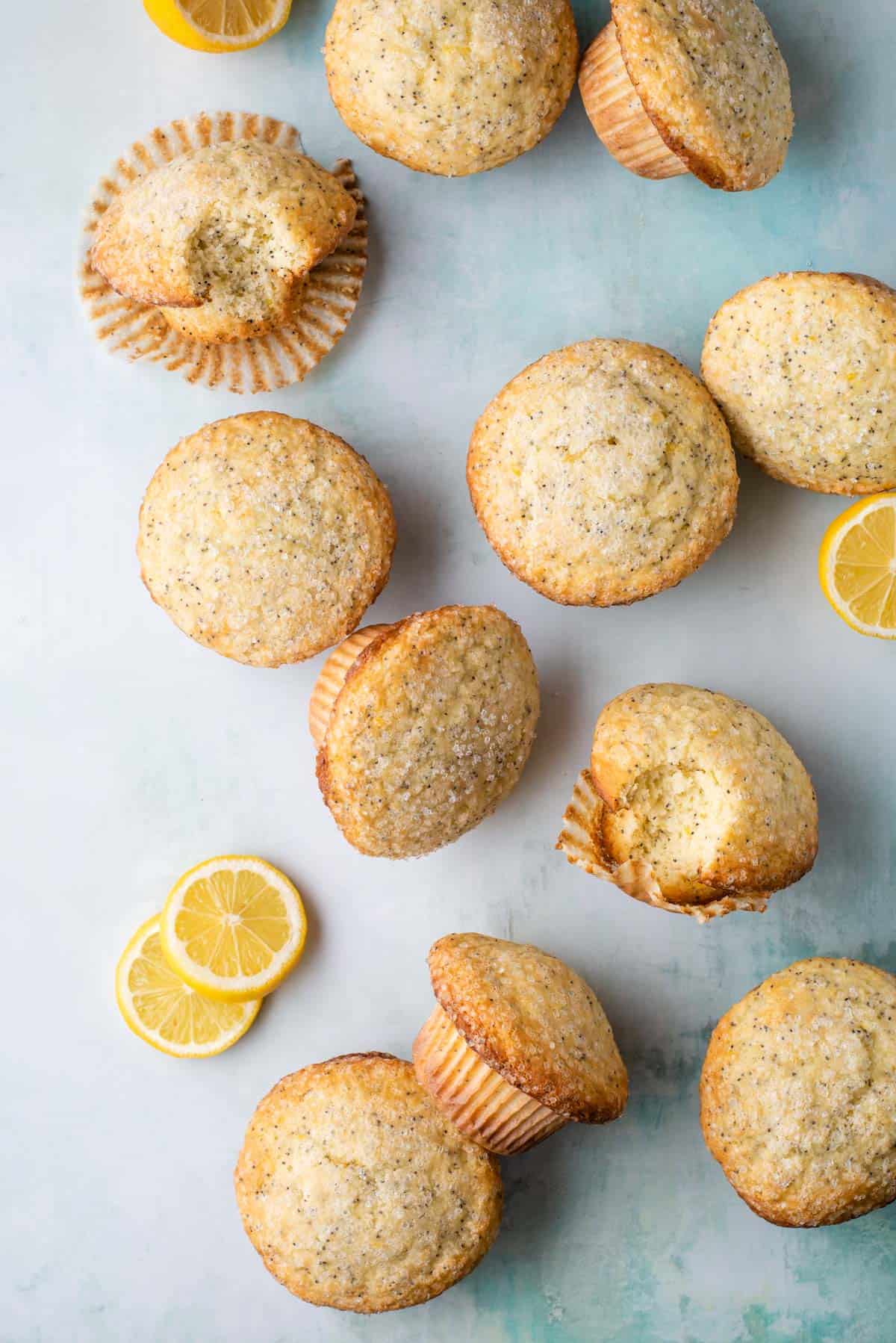 lemon poppy seed muffins arranged around, some on their sides and some sitting upright, surrounded by lemon slices