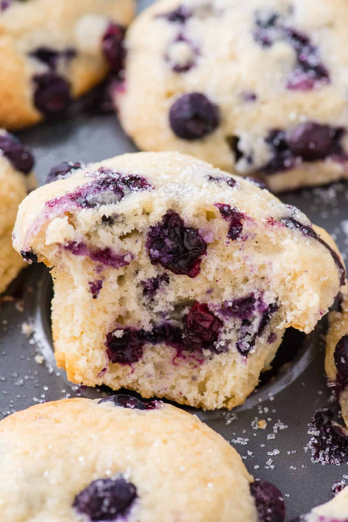 blueberry muffin with bite removed in muffin pan