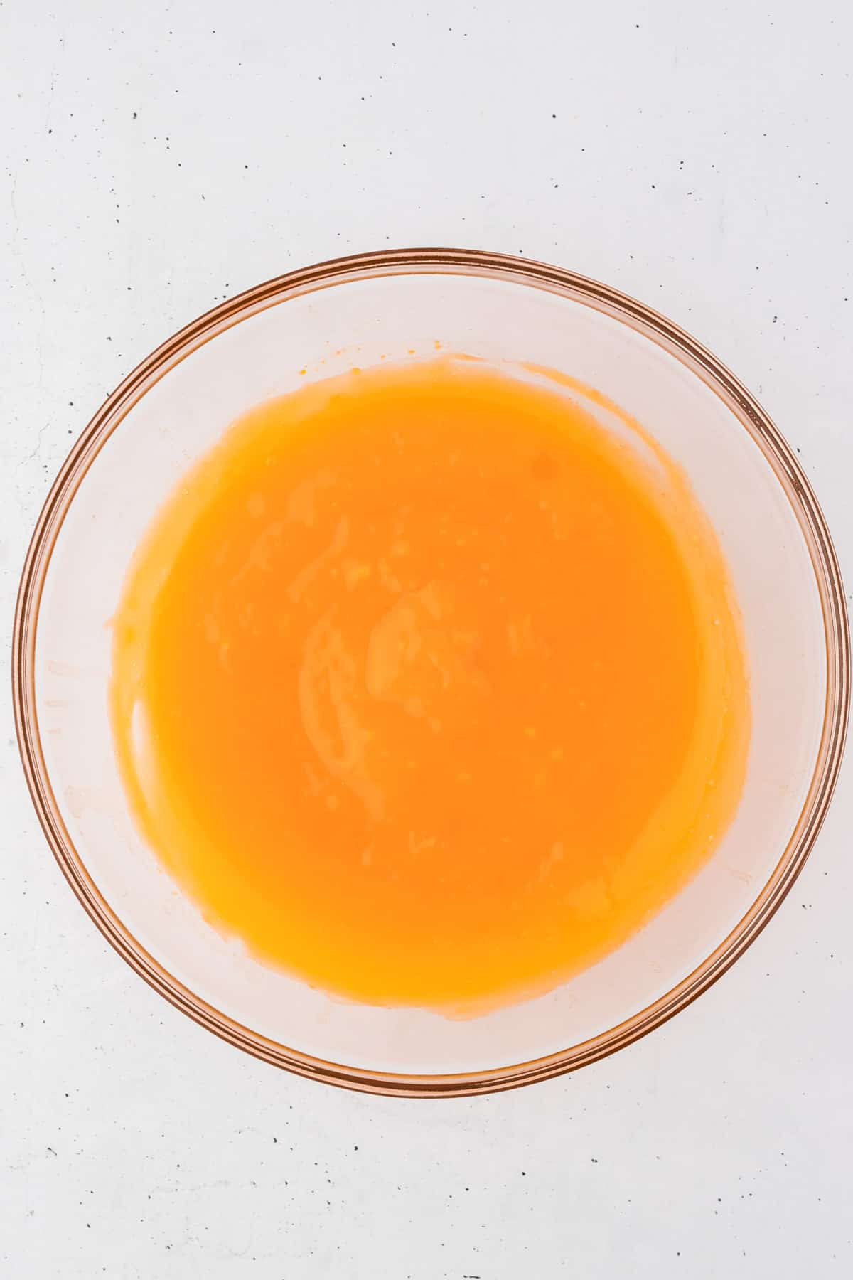 orange jello mix combined with water in a glass bowl