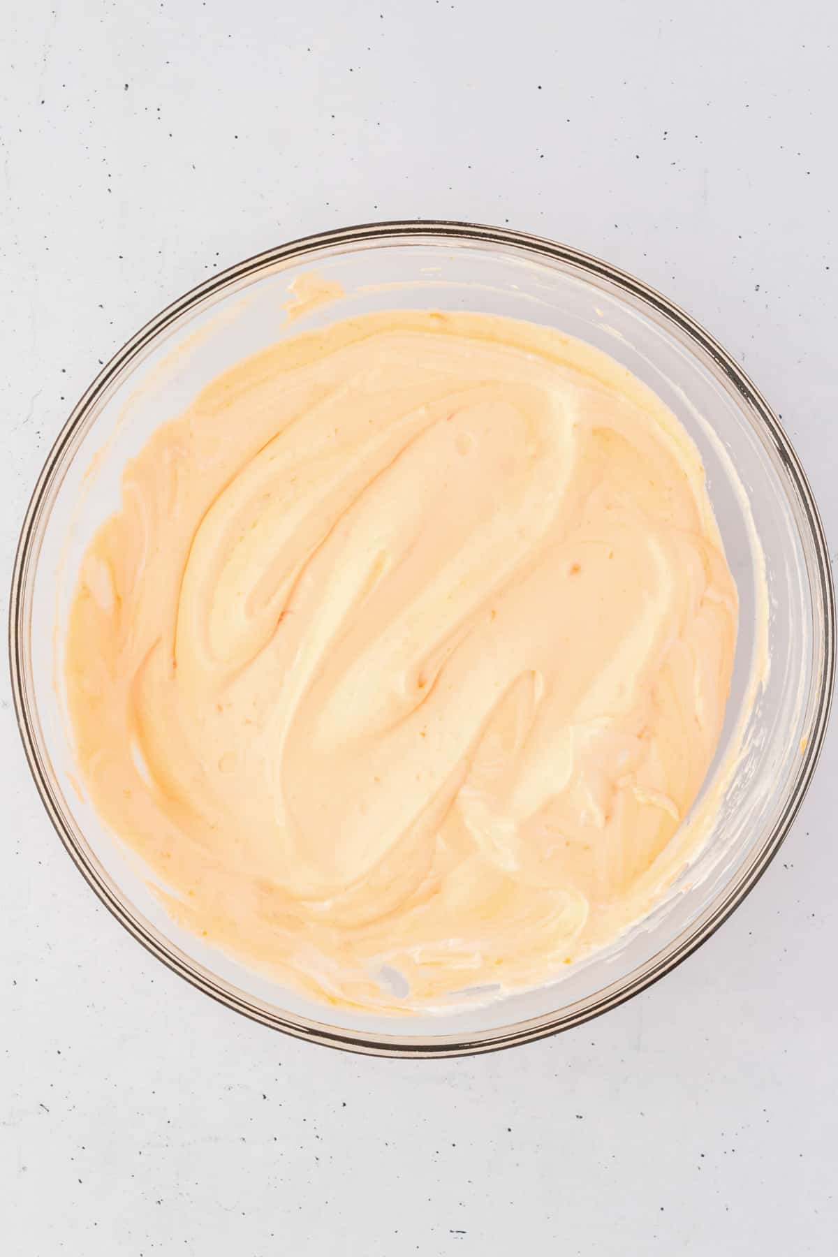 the creamy mixture for orange fluff salad in a glass bowl