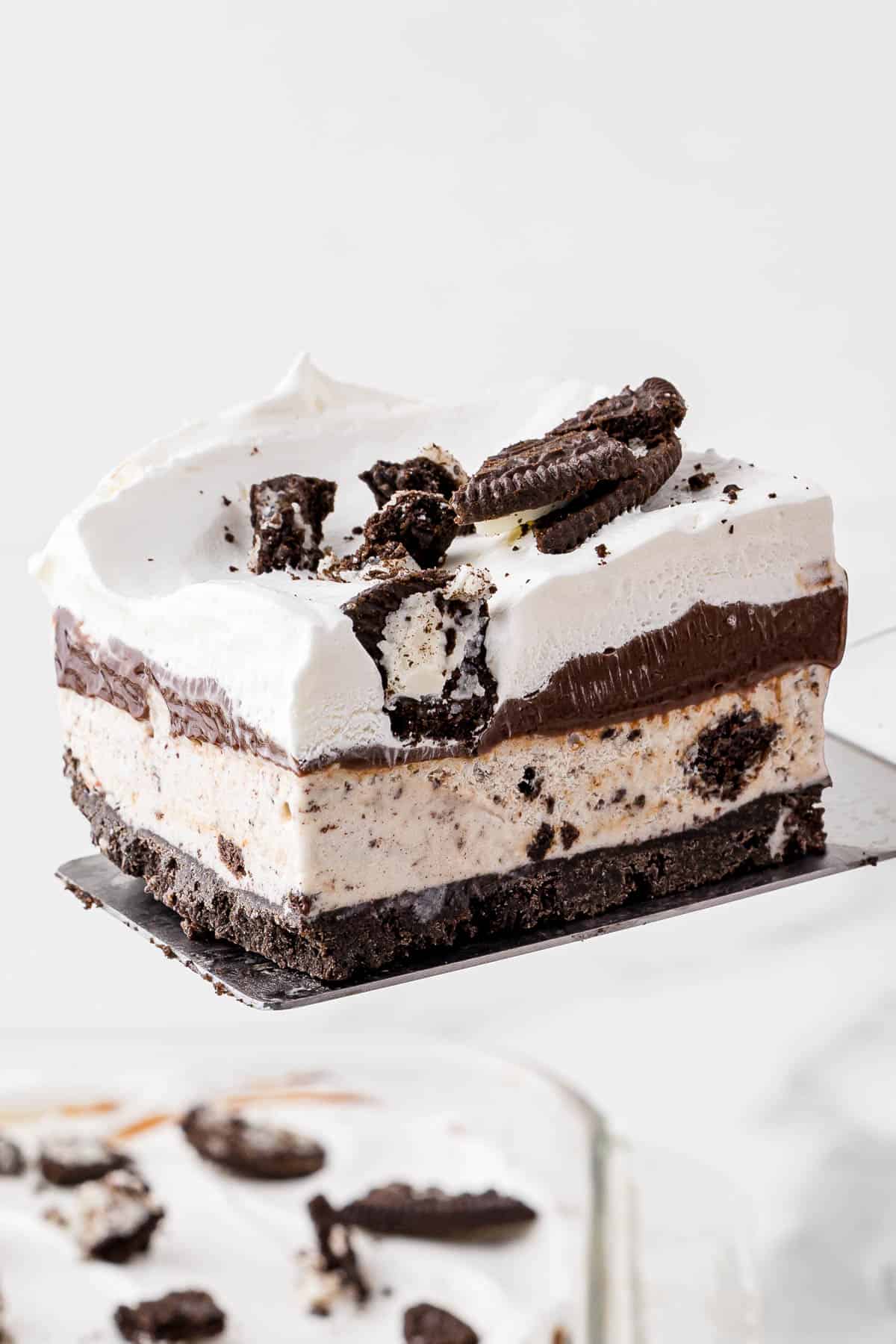 a slice of oreo ice cream cake being lifted out of a dish with a spatula