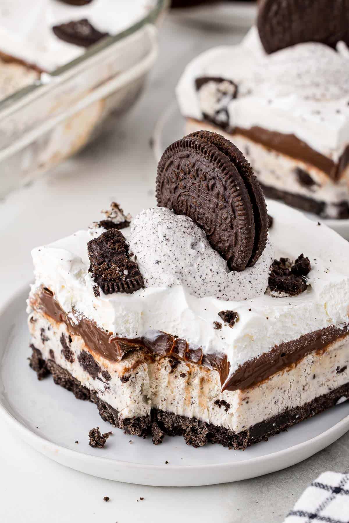 a slice of oreo ice cream cake on a white plate with a bite taken out