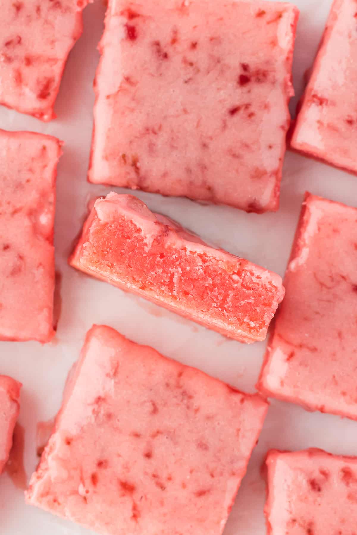 an arrangement of strawberry brownies on a white surface with the middle brownie on its side and the rest laying flat