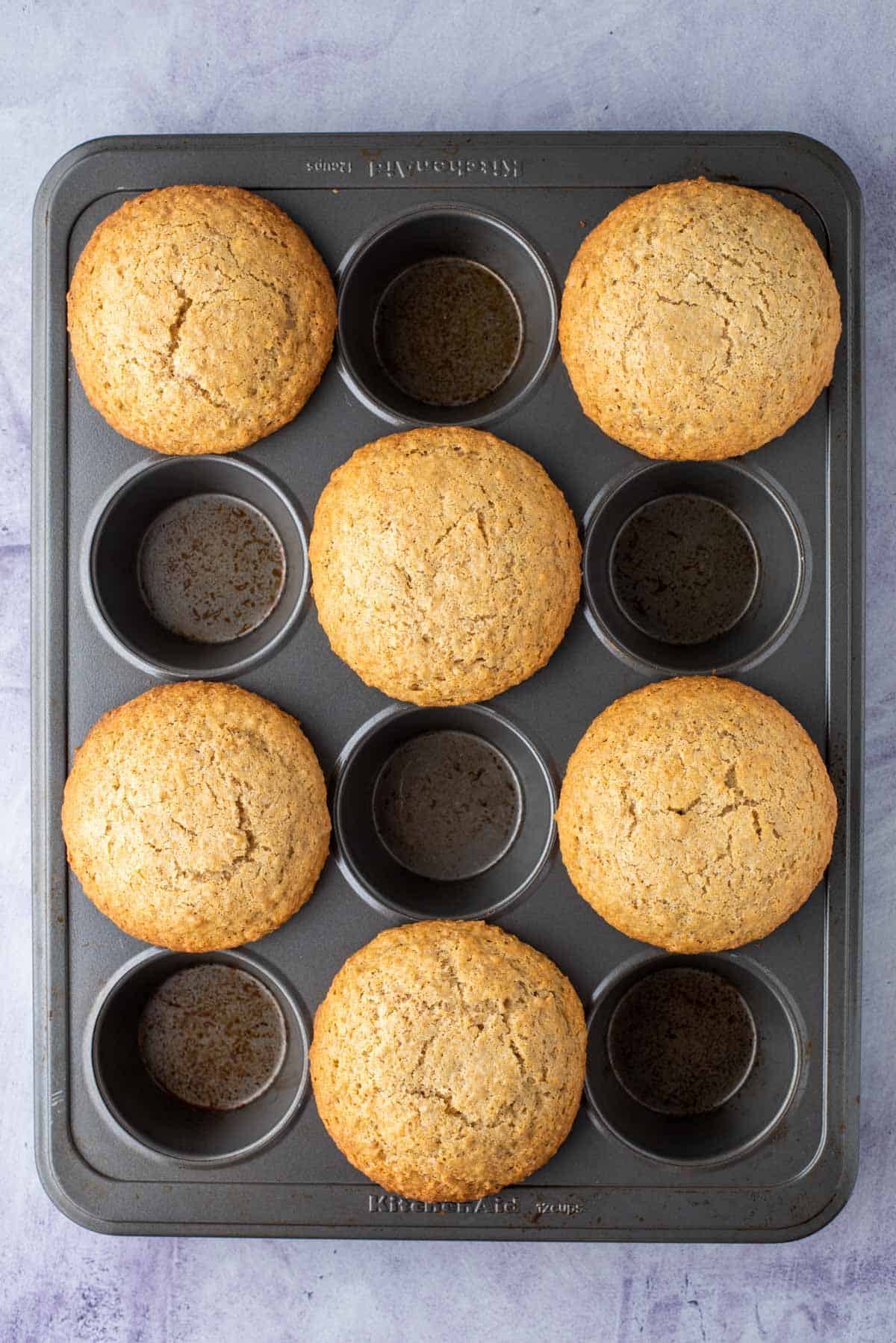 a muffin pan with a bakery style bran muffin in every other muffin spot