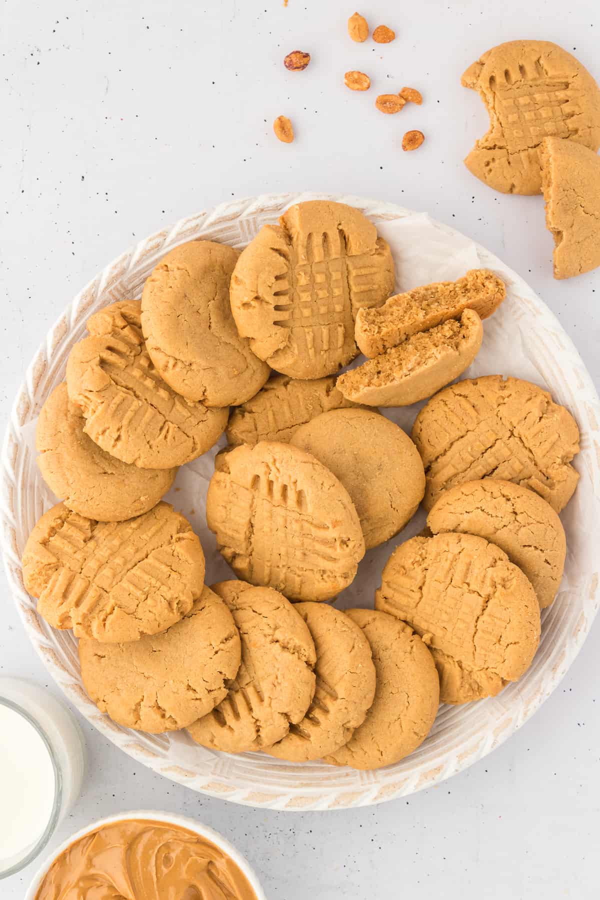 gluten free peanut butter cookies arranged on a white plate with peanuts and more cookies surrounding it