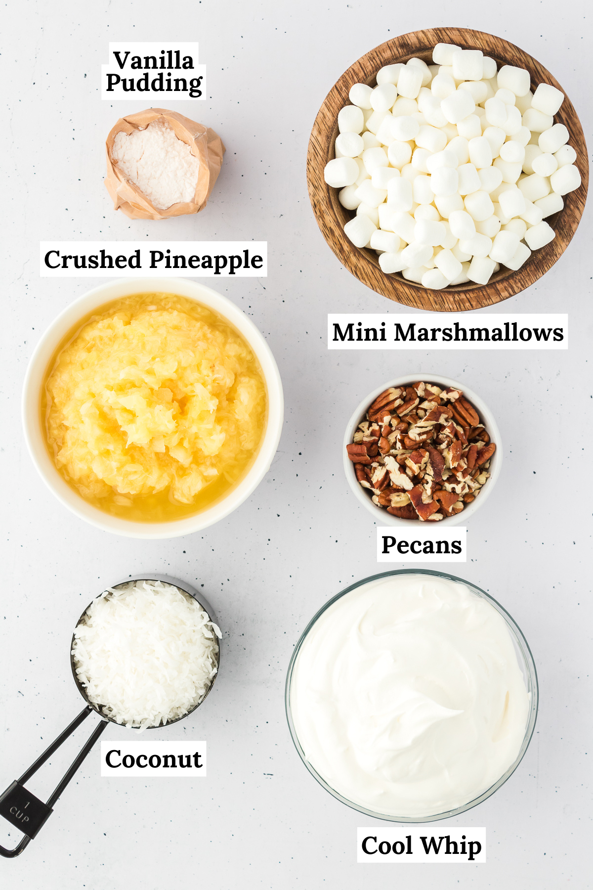 ingredients for pineapple fluff including instant vanilla pudding mix, crushed pineapple, cool whip, mini marshmallows, sweetened shredded coconut, and chopped nuts