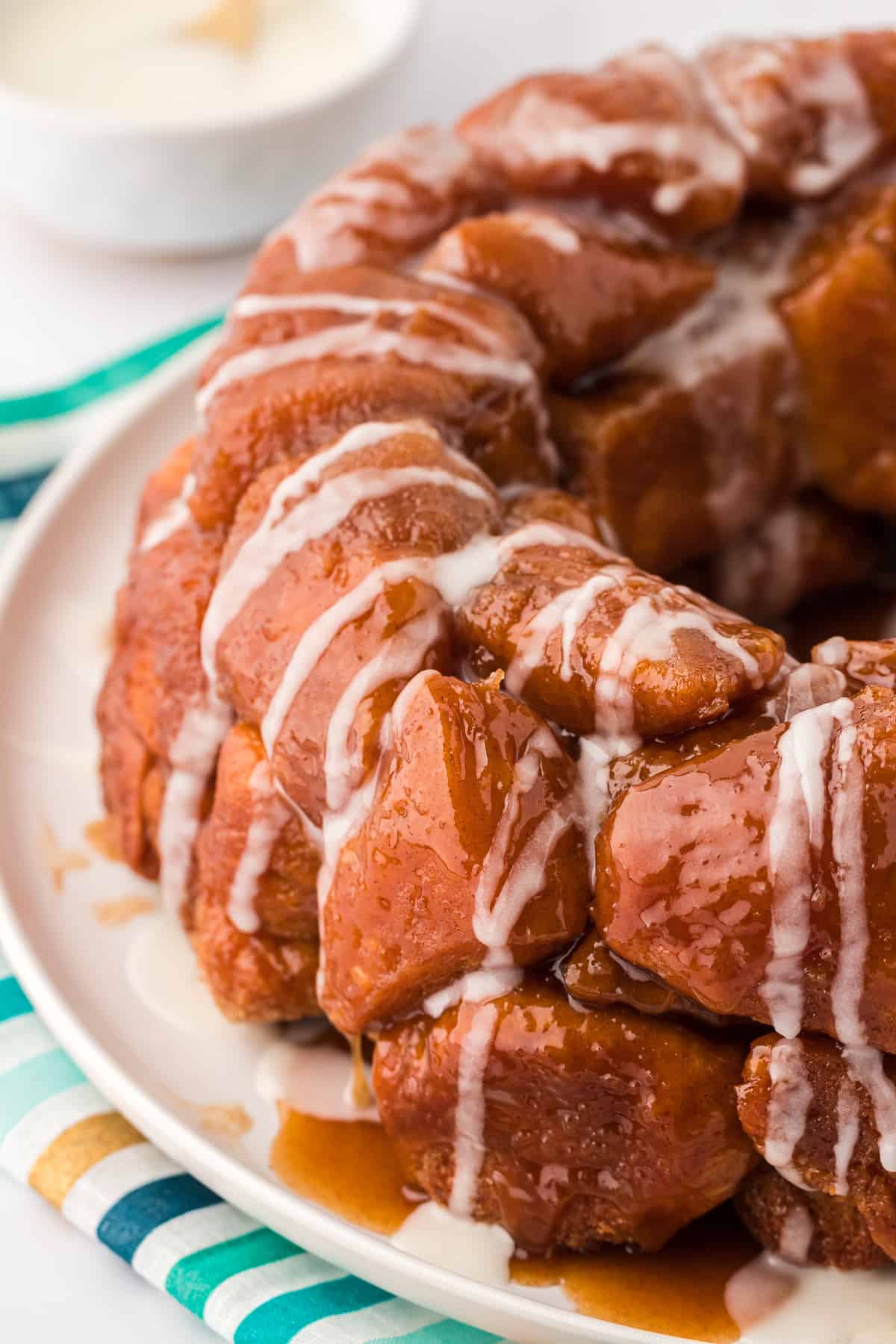 monkey bread on a white plate on a top of a gold, teal and blue striped kitchen towel