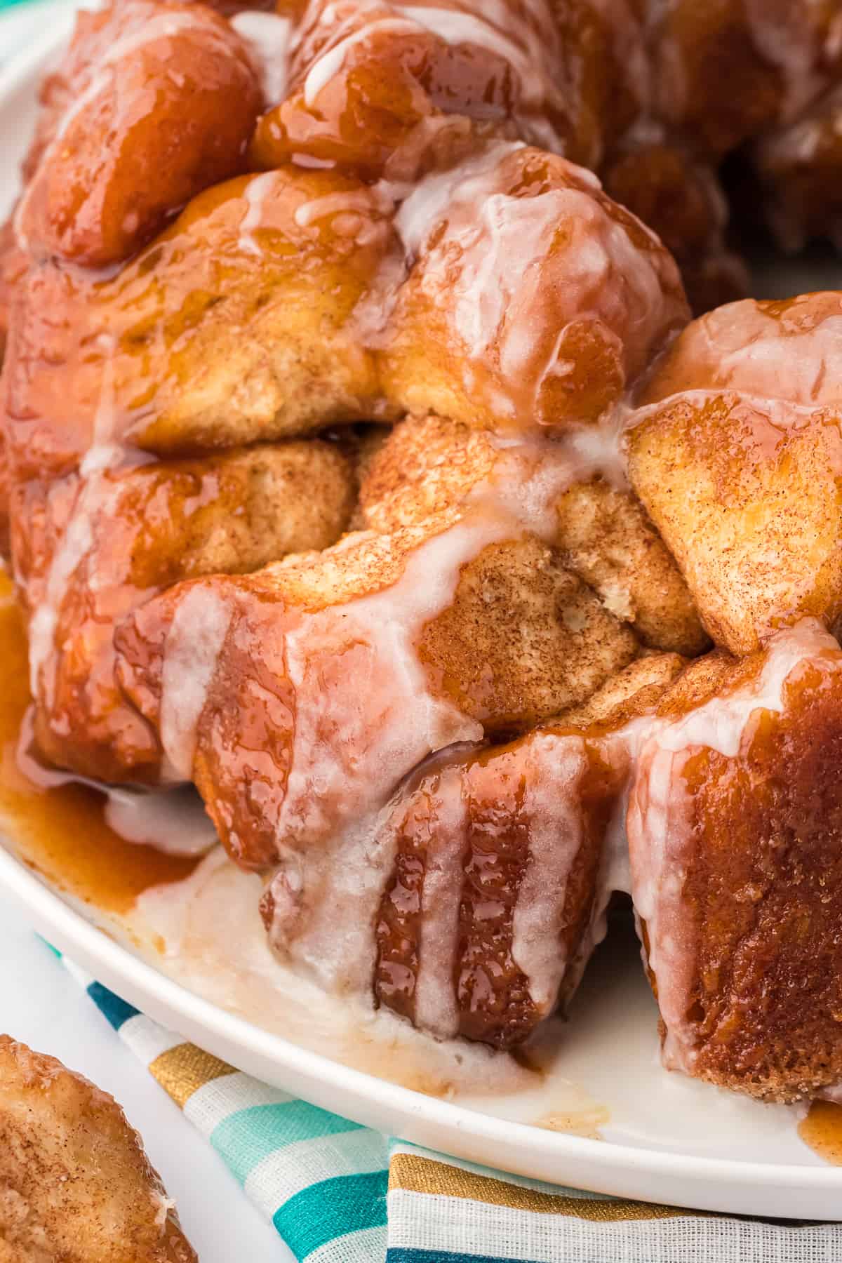 close up of monkey bread on a white plate with a colorful striped towel underneath
