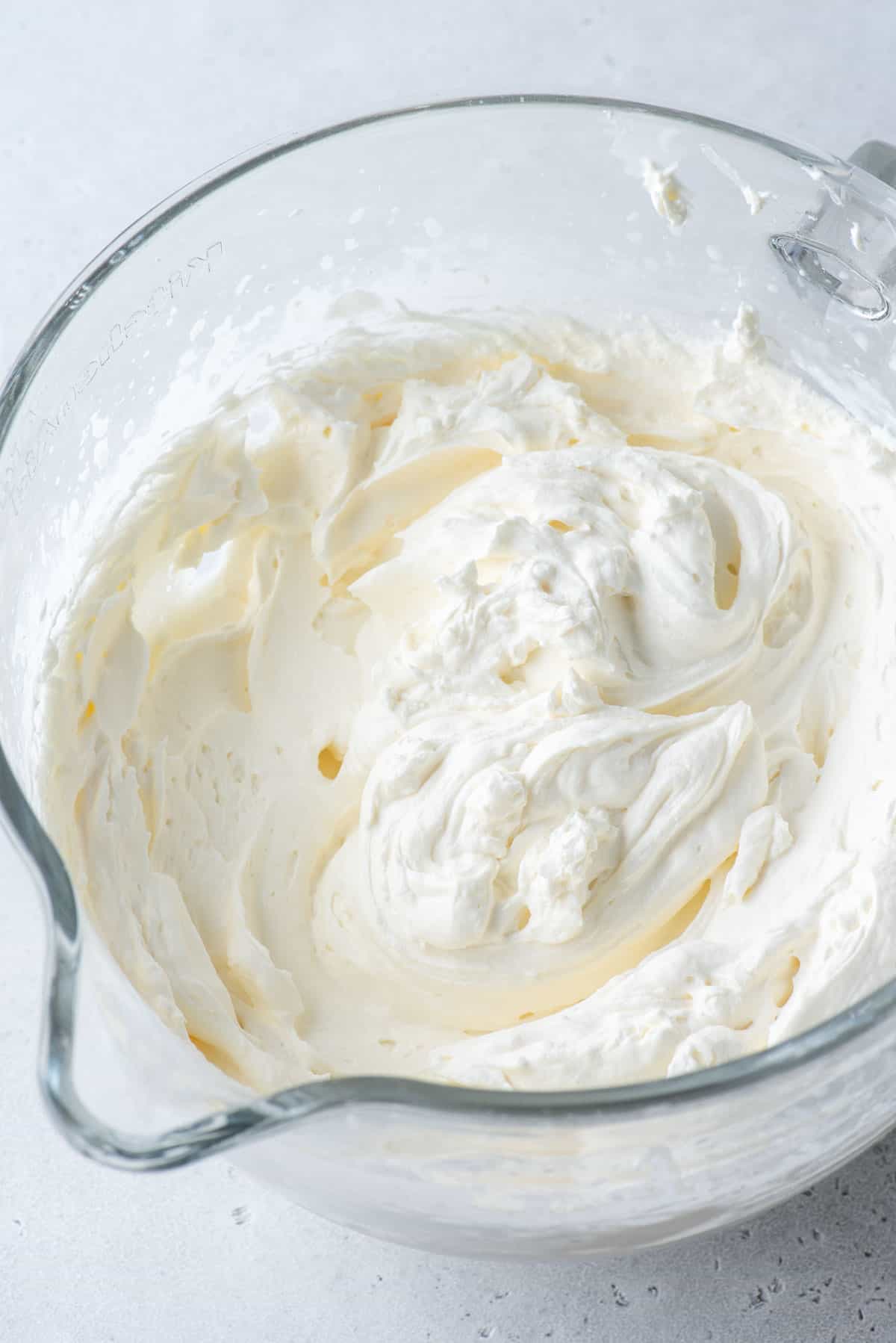 Stabilized whipped cream in a clear glass mixing bowl